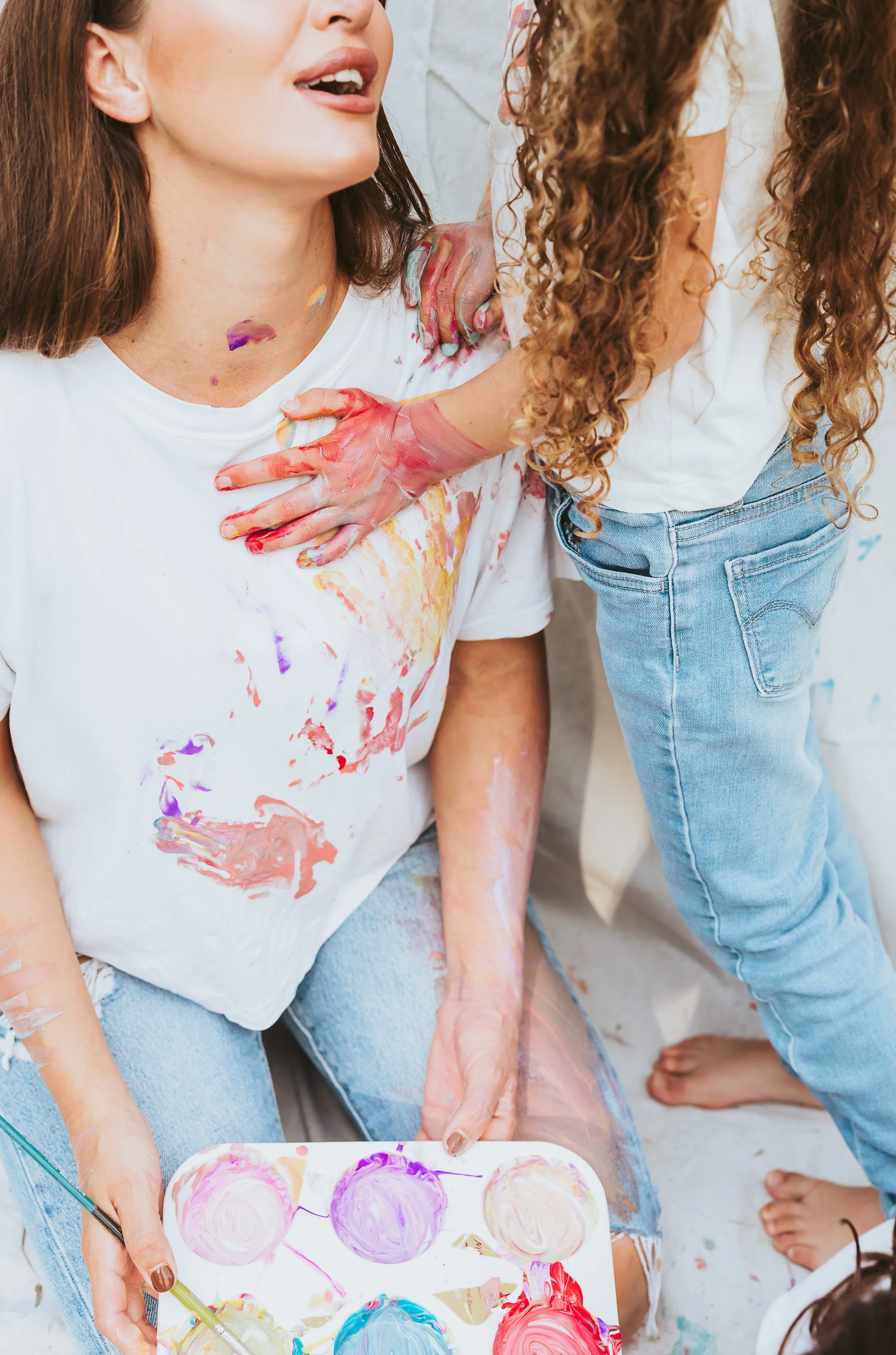 Mother and daughter enjoying a close moment during an emotional storytelling family photography session with paint mini interaction in Alberta.