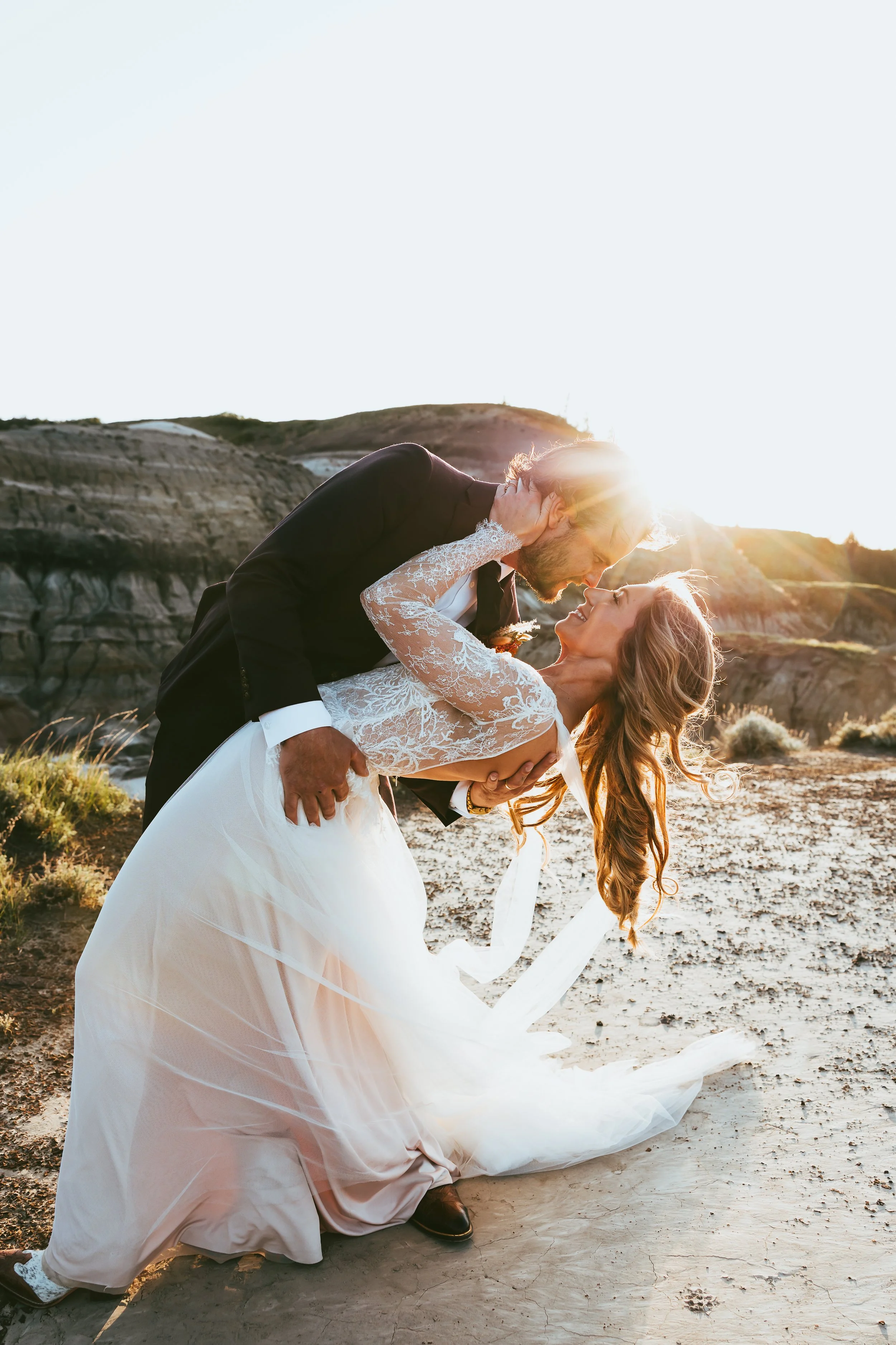Intimate bride and groom embracing during sunset elopement in the Drumheller Badlands with soft golden light and natural landscape