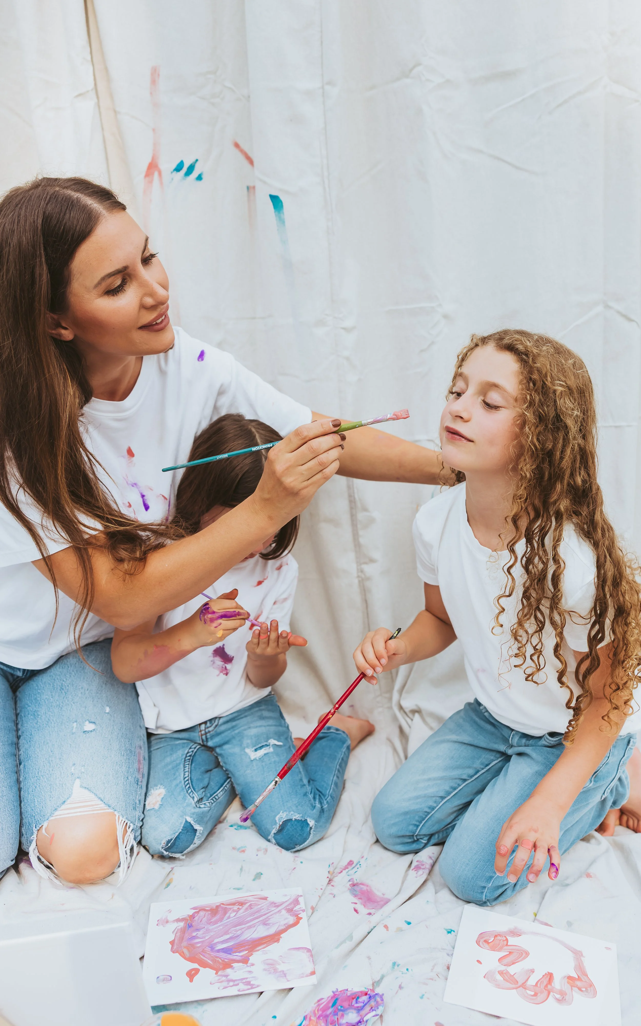 Mother gently touching daughter’s face during an emotional storytelling family photography session with paint mini interaction in Alberta.