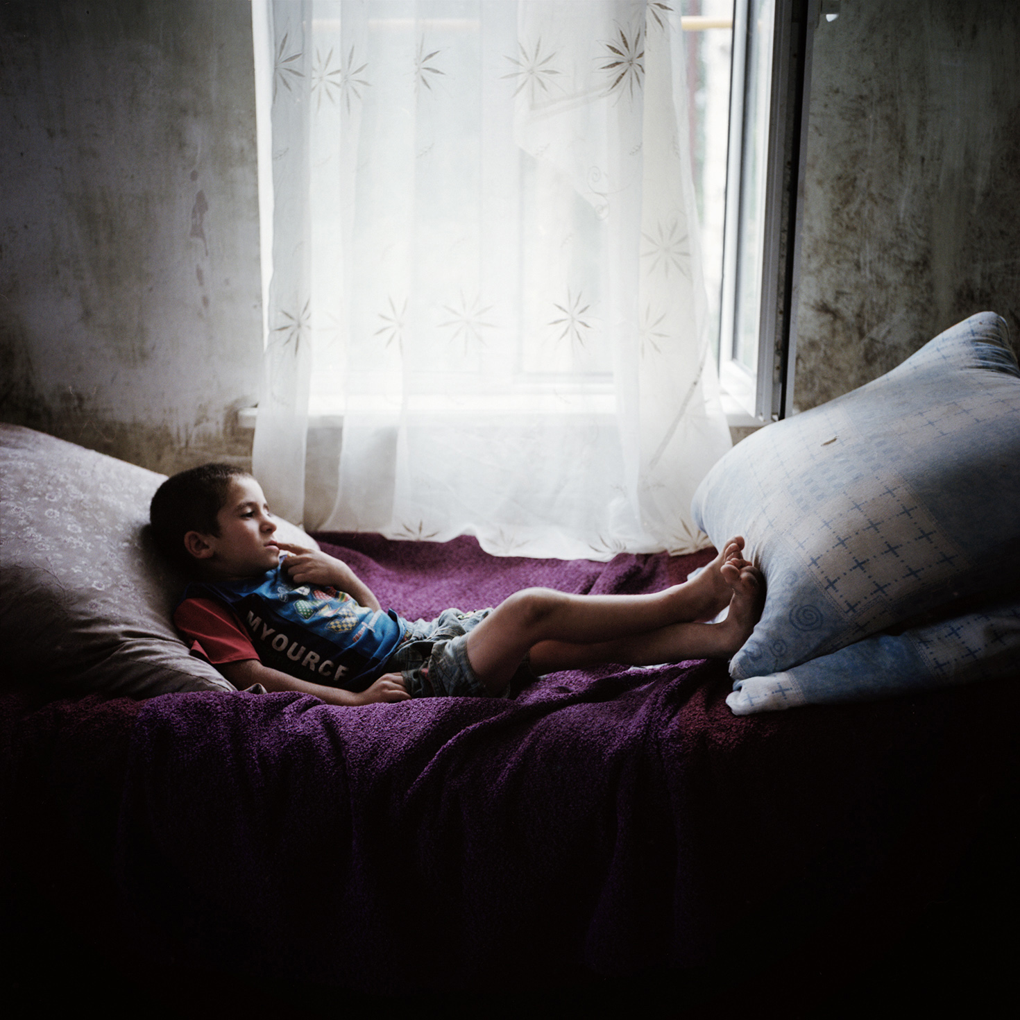  In Chouchi, a little boy from a large family in his bed, thoughtfully. 