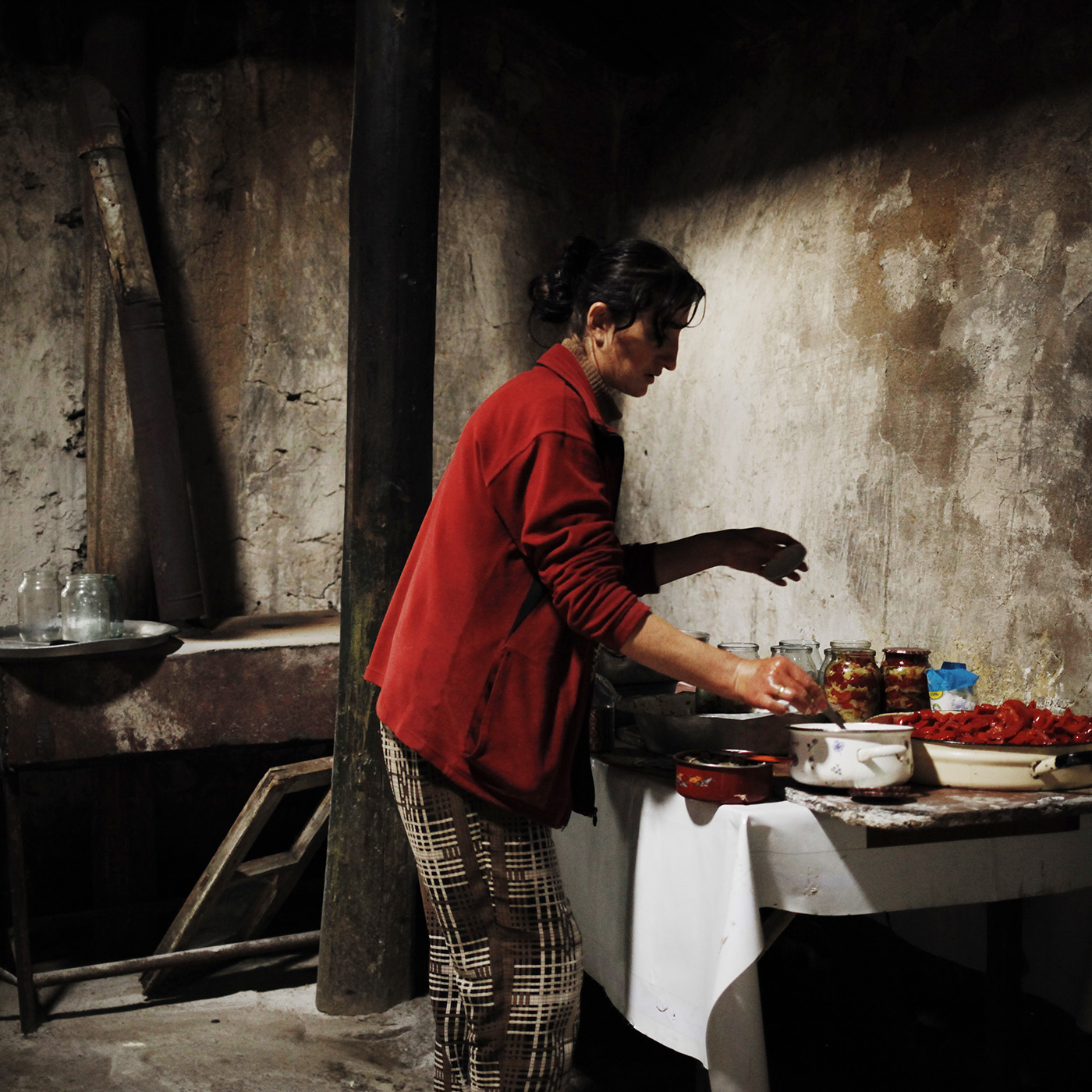  Anoush is preparing canned peppers in the outbuilding of the house. 