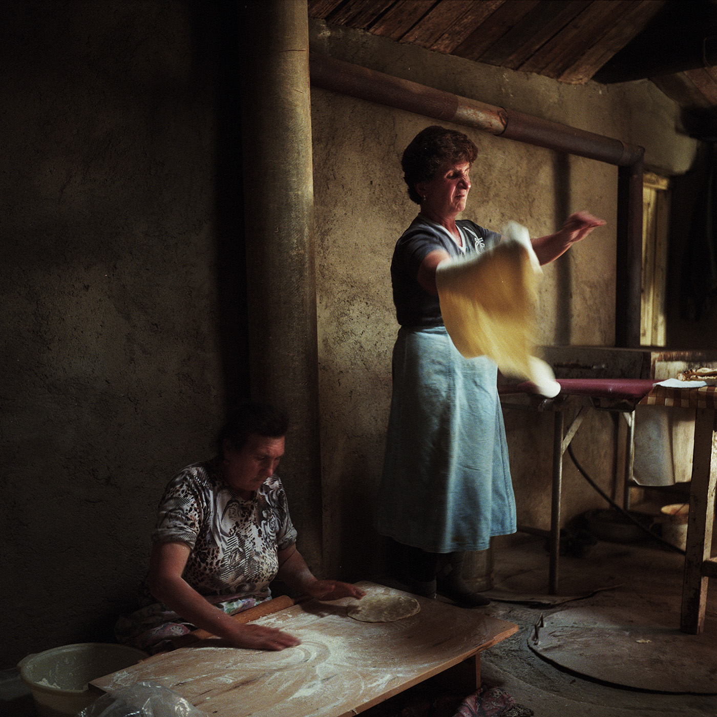  Asya (right) cooks lavash with her neighbor Venera (left). The 3 daughters of Asya are married to men working in Russia. Her young son Artashes studies economics and works every summer in Russia. Once he finishes his studies, he intends to work in R