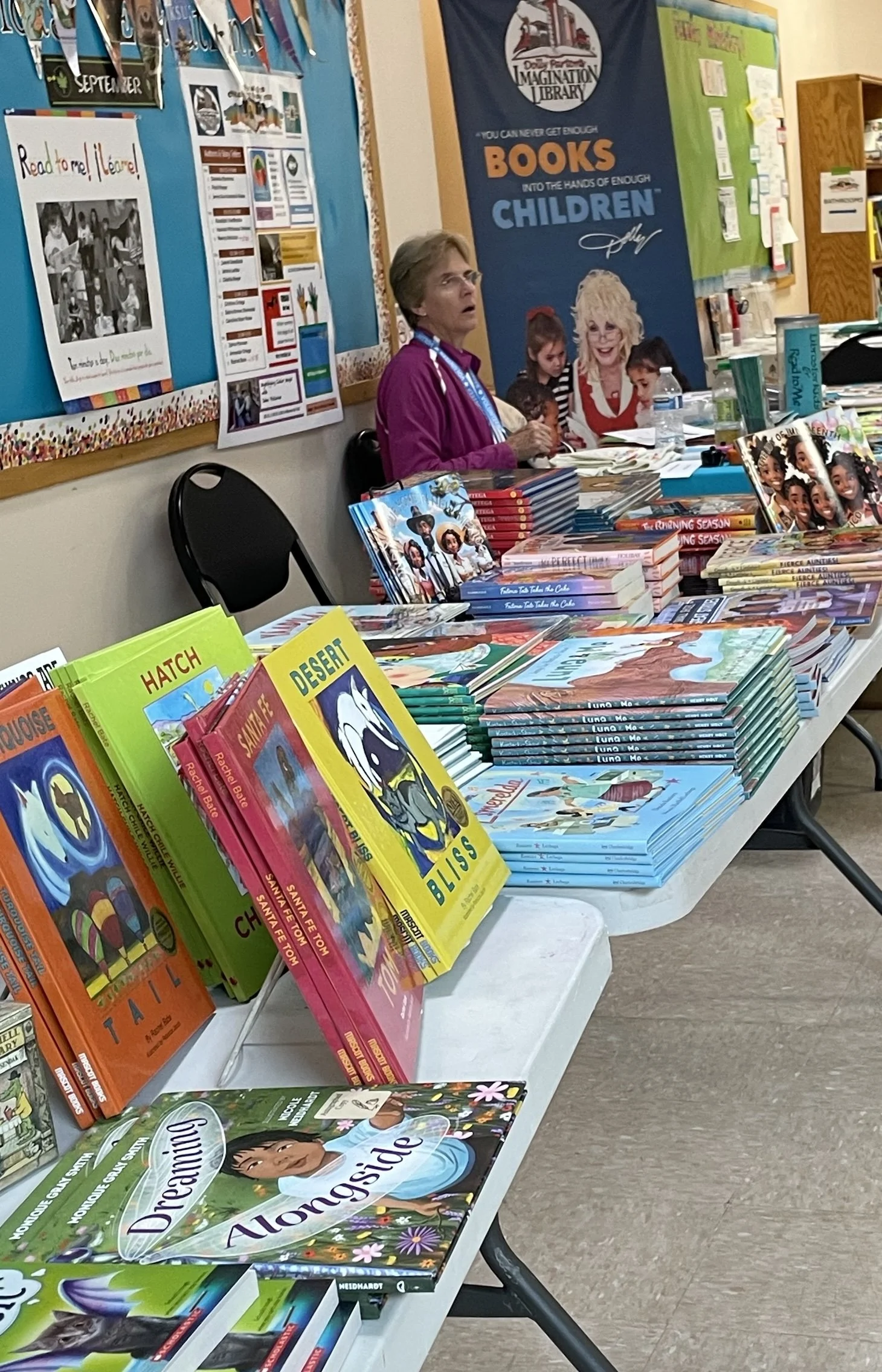 Libros Treasurer Linda Contos next to participating authors’ books at the New Mexico Children’s Book Fair.