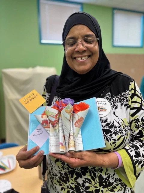 Author Khadijah Van Brankle holding a “book bouquet” gift created my Libros volunteer Mary Beth Thorn.
