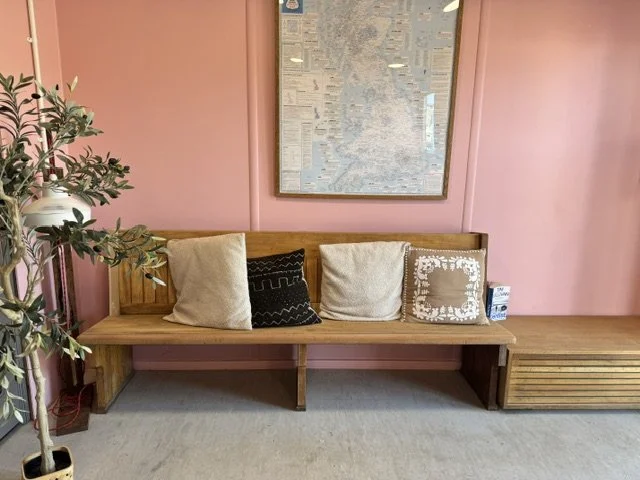 A wooden bench with cushions in a self-service launderette