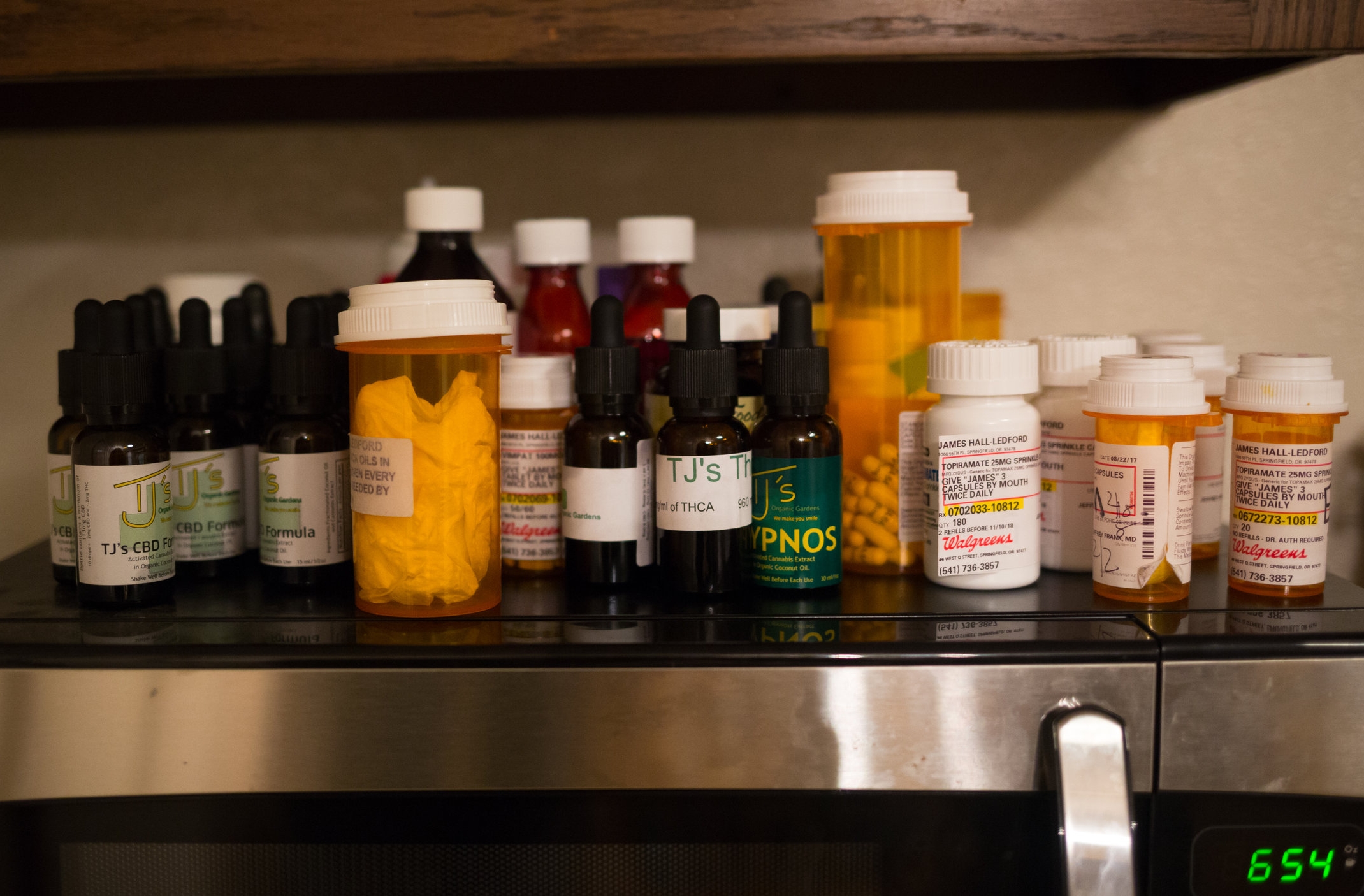  A various combination of pharmaceutical and cannabis derived medicines above the kitchen microwave. James is still not entirely pharm-free. He remains on a low dose of his former prescribed treatment along with the CBD, THC and THCA oils. 