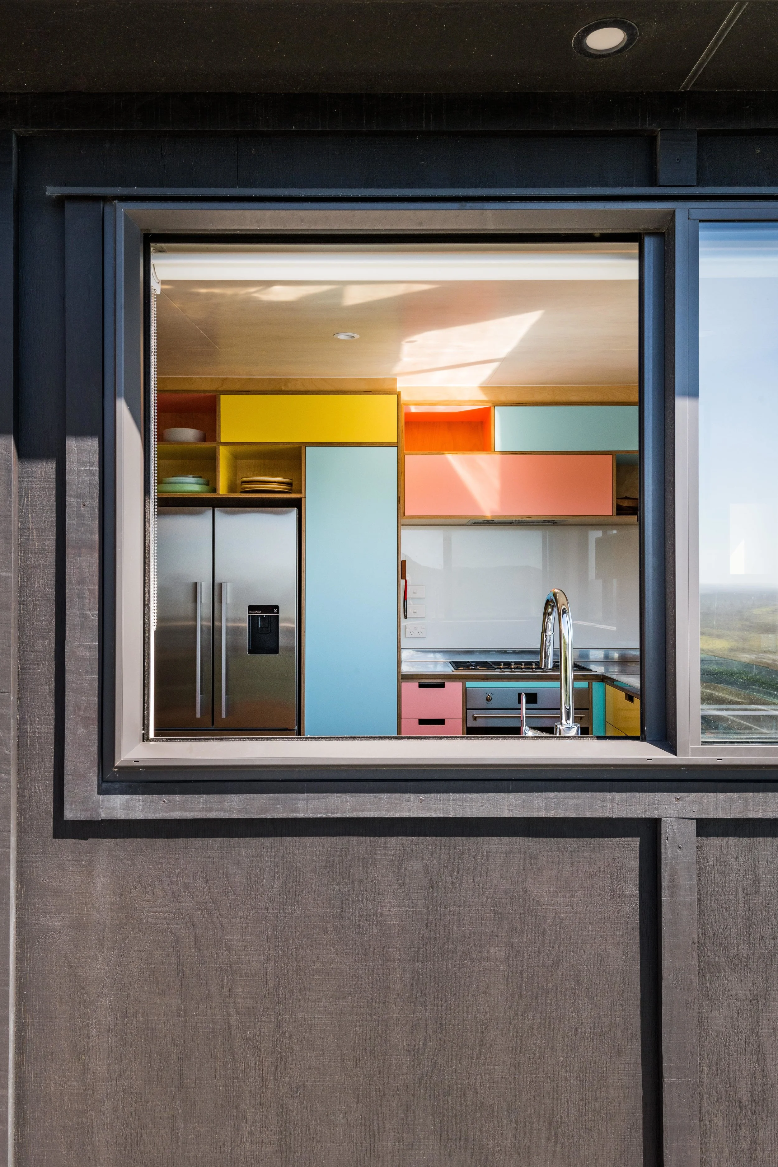  When refitting this original run down coastal home, our first priority was to stick to the true ethos of the kiwi Bach. Low key, low maintenance and welcoming.  Inside the black plywood box is a space filled with playfully coloured cabinetry, original wooden flooring, eclectic art and old school furniture all culminating to create a refreshed and quintessential holiday home. 