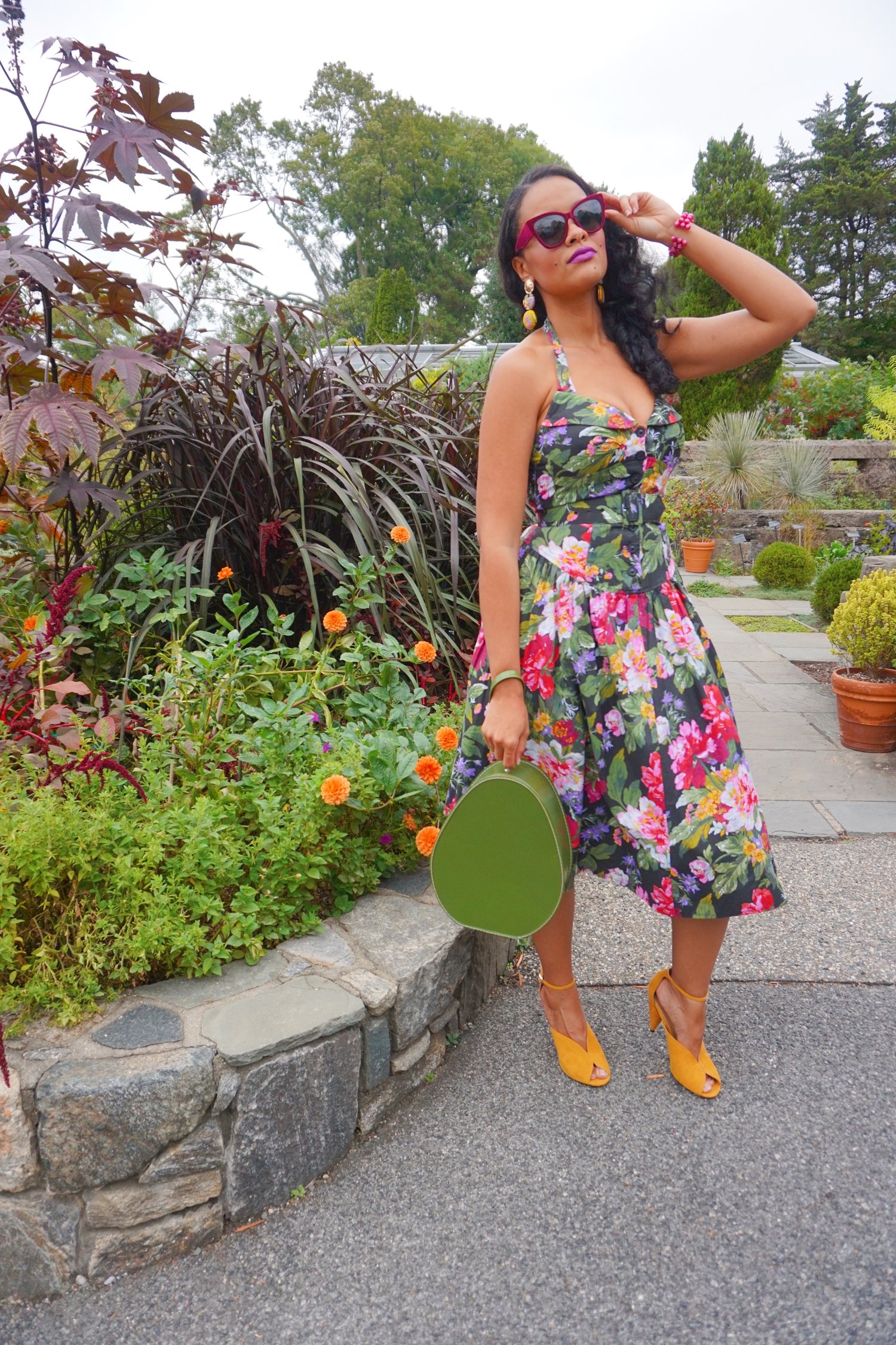 Mixing the decades - Krystle styles a 50s vintage floral halter dress with 40s inspired modern heels in a mustard color, tiered fabric button earrings, velvet sunnies in a deep wine color, and vintage beaded bracelet in purple that belonged to her mom. A vintage train case in an avocado green serves as her purse. <3