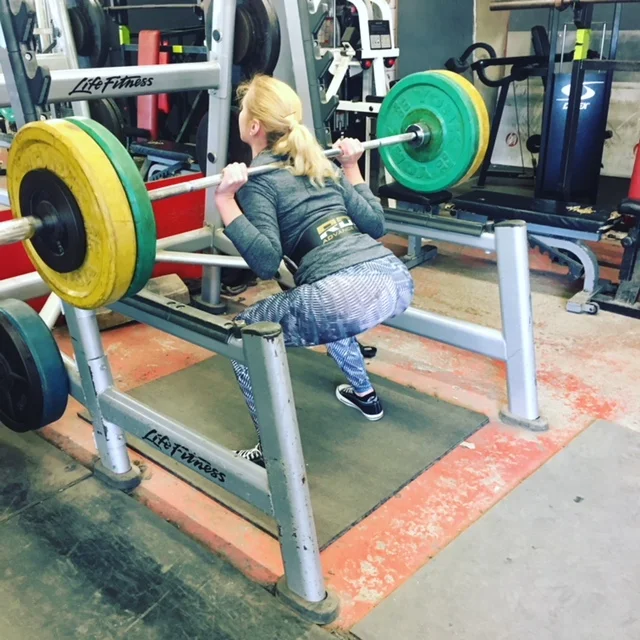 A client performing a barbell squat during training