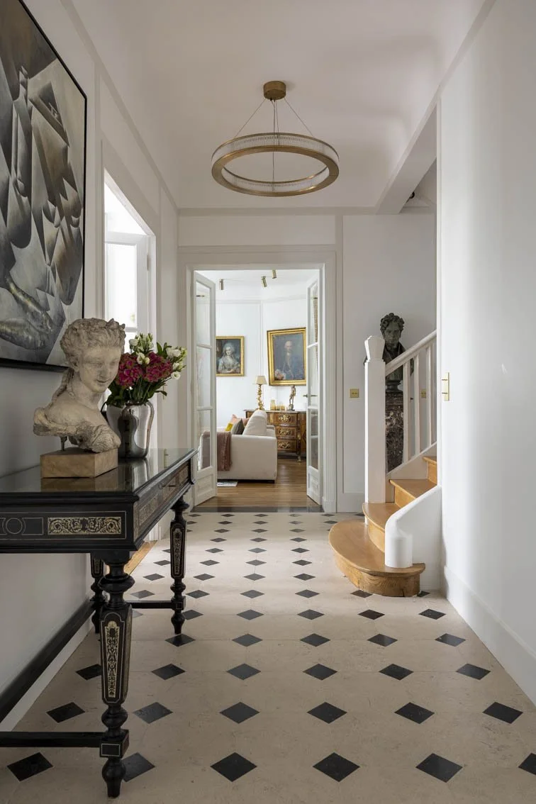 Le sol de cette grande entrée a été changé: le parquet à lames droites à été déposé et remplacé par une belle pierre de Bourgogne avec des cabochons. Un beau miroir sur mesure a été fixé sur le mur du fond pour agrandir l’entrée et donner de la pro