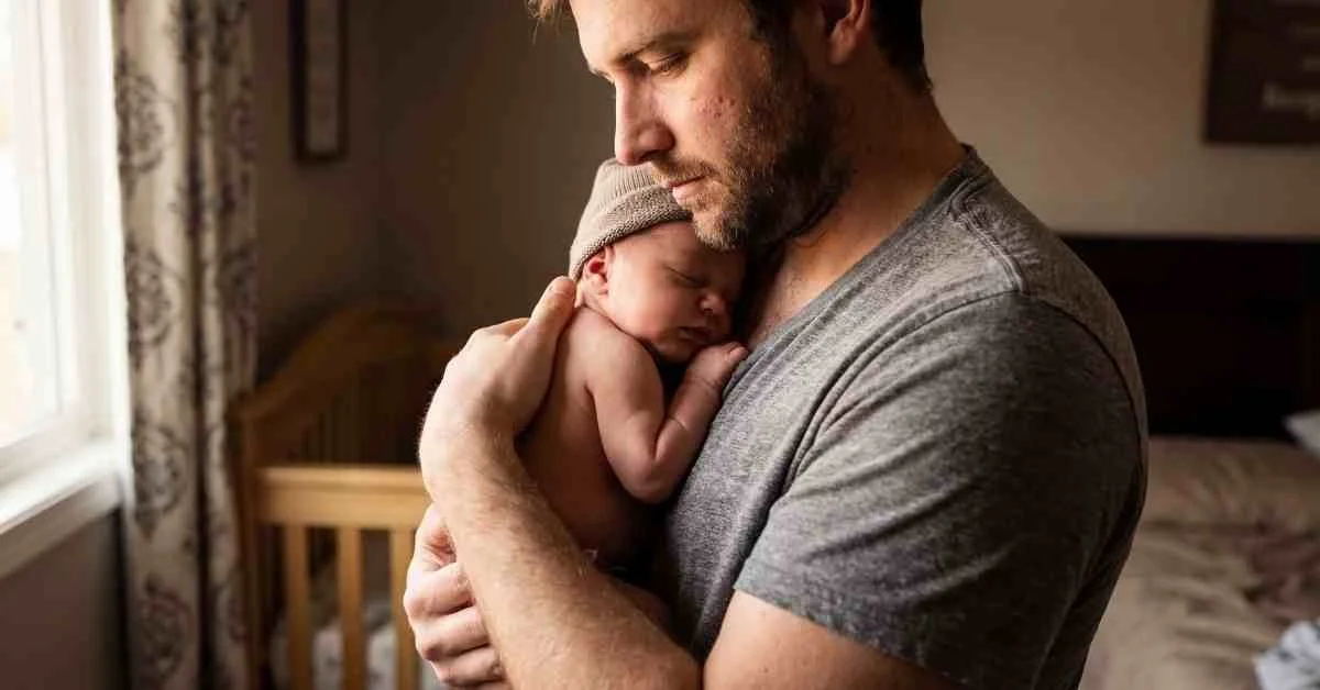 Profile of father cuddling newborn by window.jpg