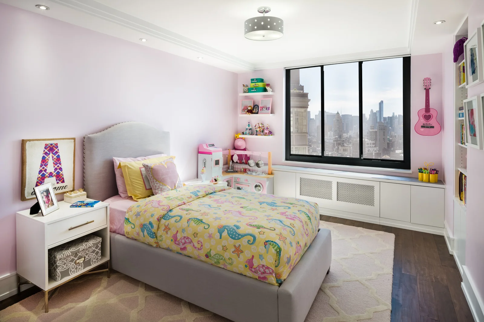 We designed the kids room with pink walls that don't offend and a big girl bed with plenty of room to add a desk and with a built-in for toys and games. The feature wall with the floating shelves provide enough space to display art work and creations by the young creator. 