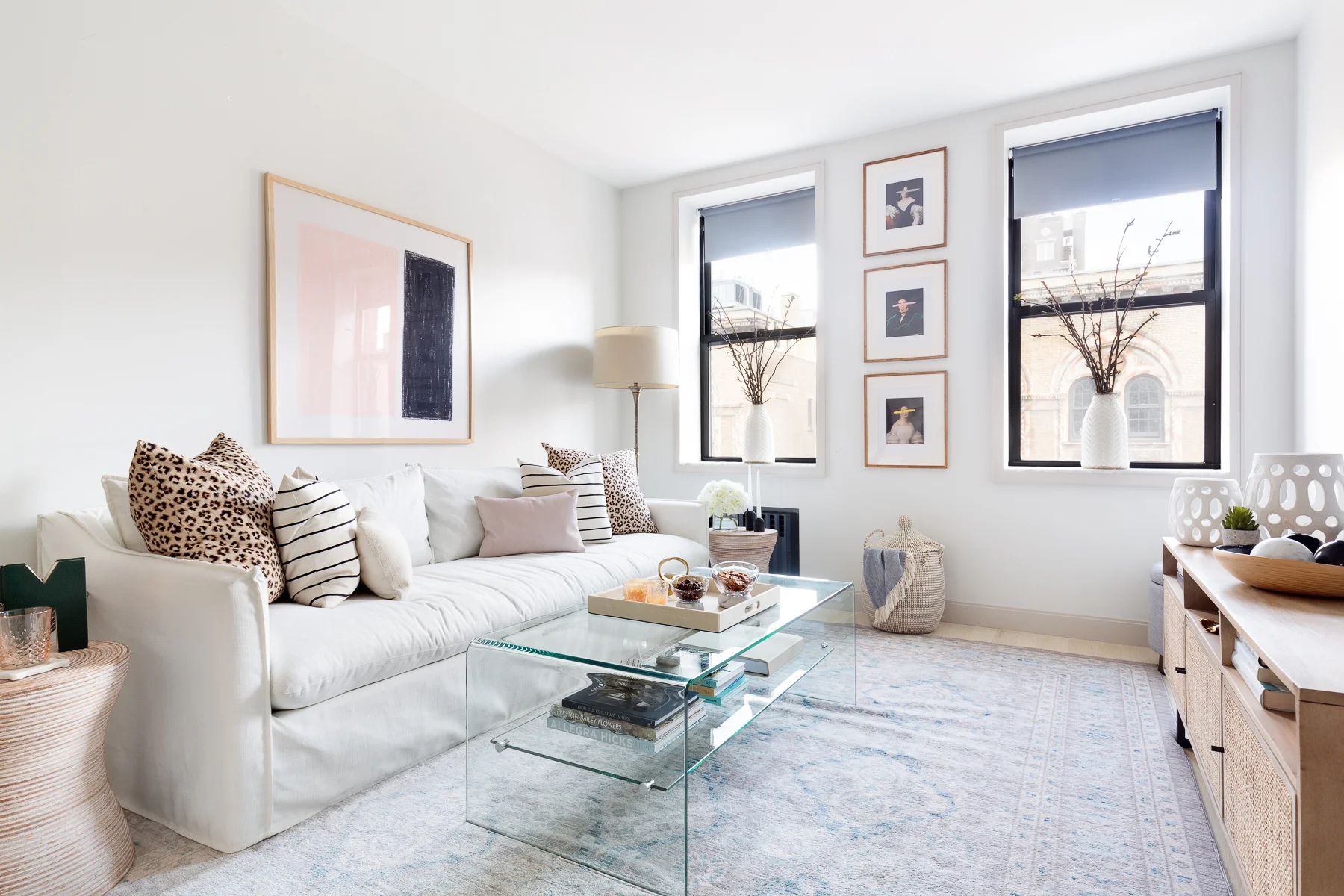 Neutral mood with layers of whites, grey, and natural woods. As always, I started with the layout and managed to fit a larger sofa than the clients thought we could fit. Every cushion, the play with the sizes and material, the color and pattern, the throw is a well thought out design decision. The art installed vertically between teh two windows and the vases with the cherry blossoms are unique design features that play up the exsiting bones of the apartment.