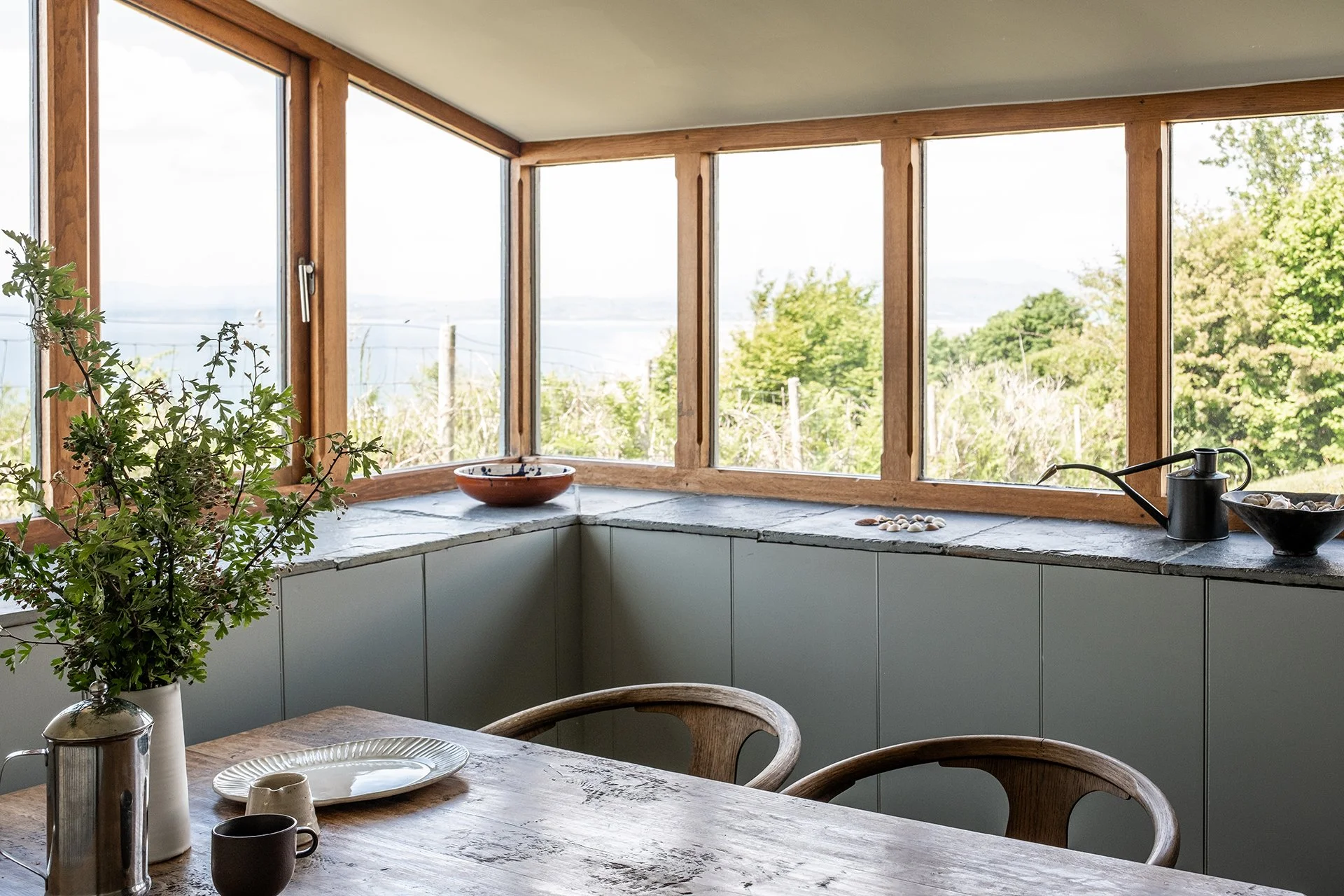 kitchen luxury home interior design with modern kitchen units, slate worktops, bespoke real wood table with wooden chairs, ceramic tableware and vase