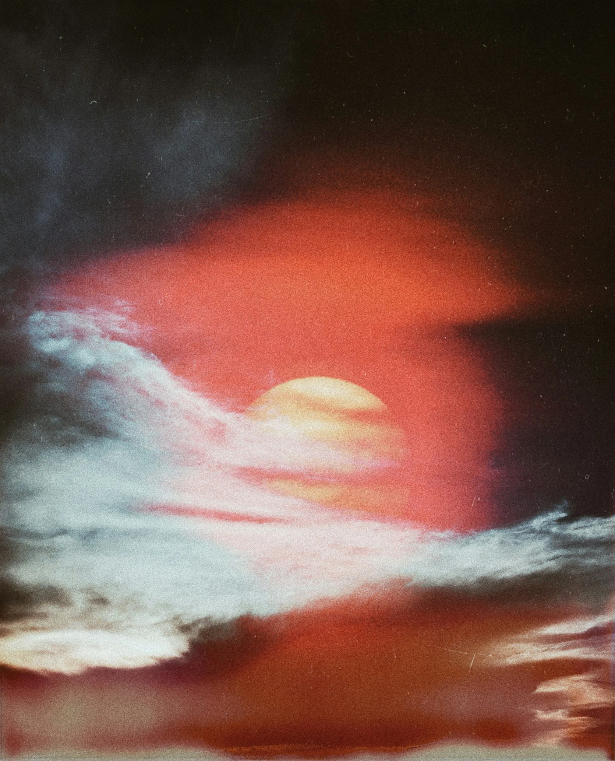 A colorful abstract image resembling a sunset with clouds, featuring vibrant red, orange, yellow, and dark hues.