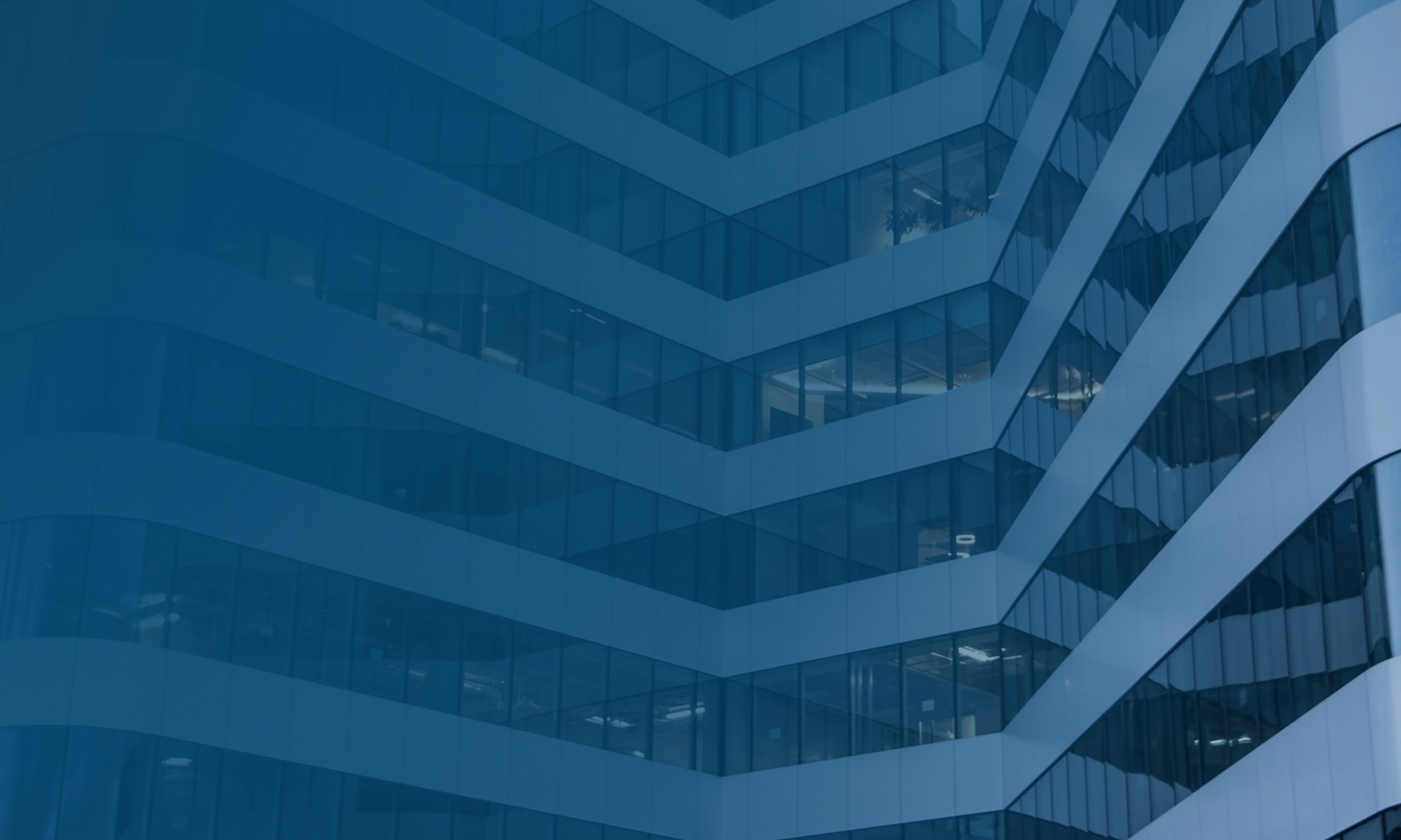 Close-up of the exterior of a modern office building with reflective glass windows and geometric architecture.