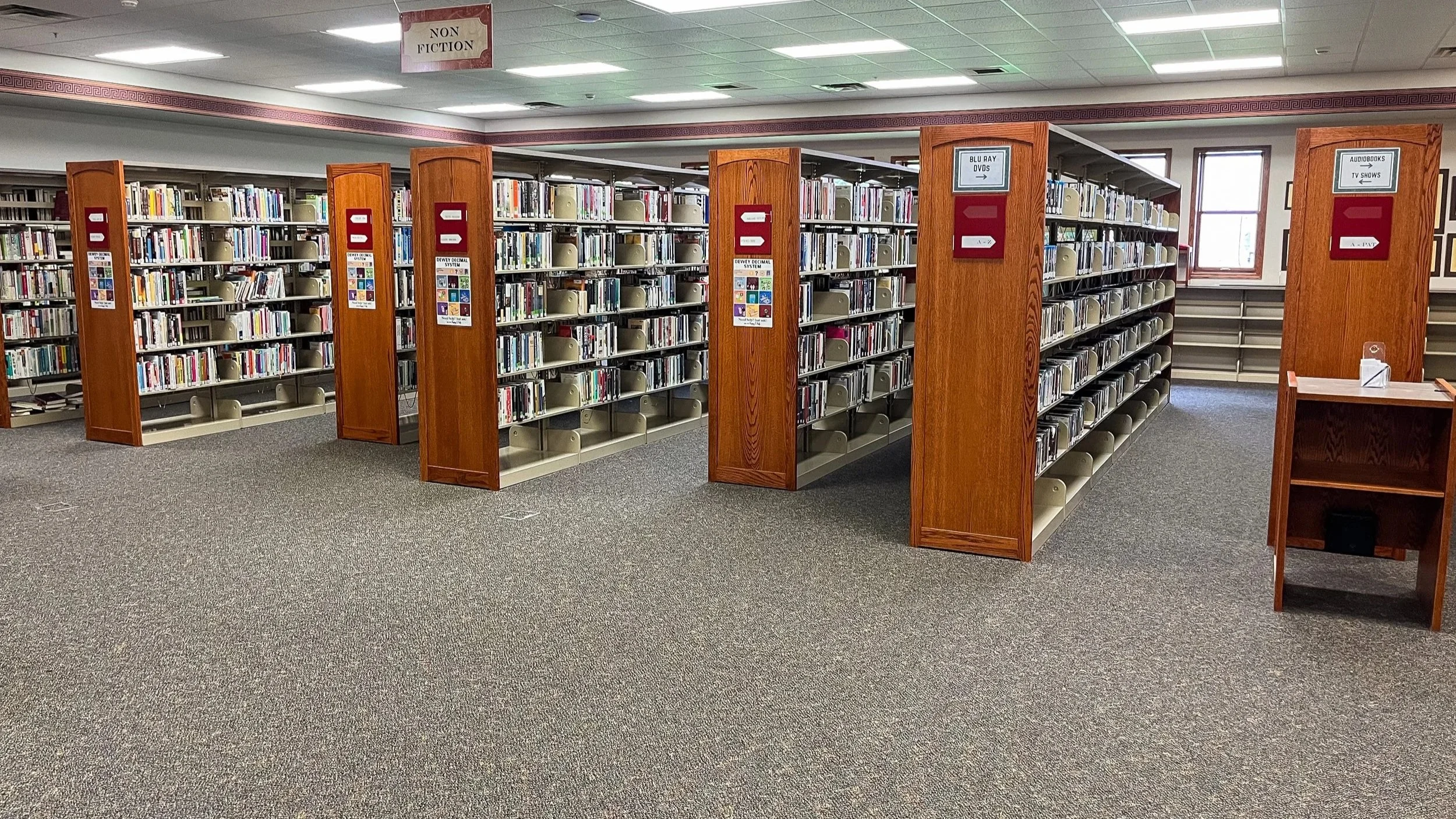 Hillsdale Michigan library stacks with gray commercial carpet flooring after Seelye Group LTD carpet replacement project