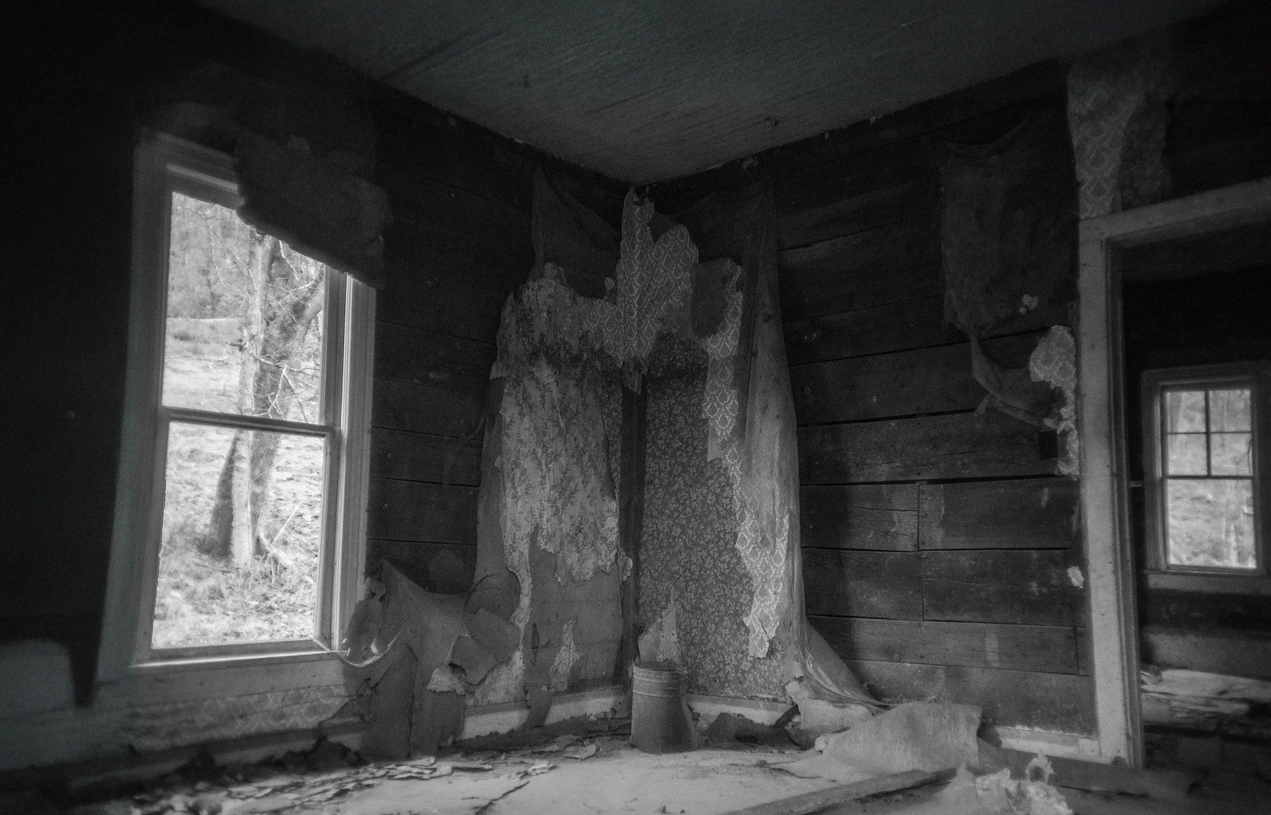 Interior of an abandoned farmhouse with peeling walls and a bright window, black and white photograph from My Tennessee by Adam CK Vollick