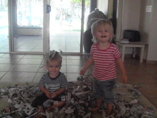 Twins Anika and Seb playing with ripped newspaper
