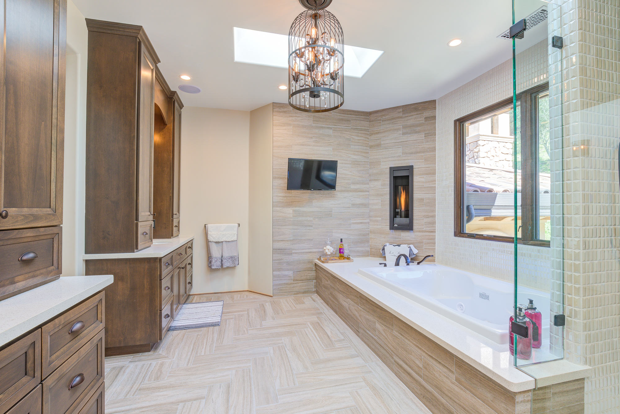  Italian porcelain tile forms a pristine herringbone pattern on the master bathroom floor and on the master shower walls.&nbsp;Richly appointed plumbing fixtures and a vintage birdcage crystal chandelier elevate this master bathroom to the likes of a