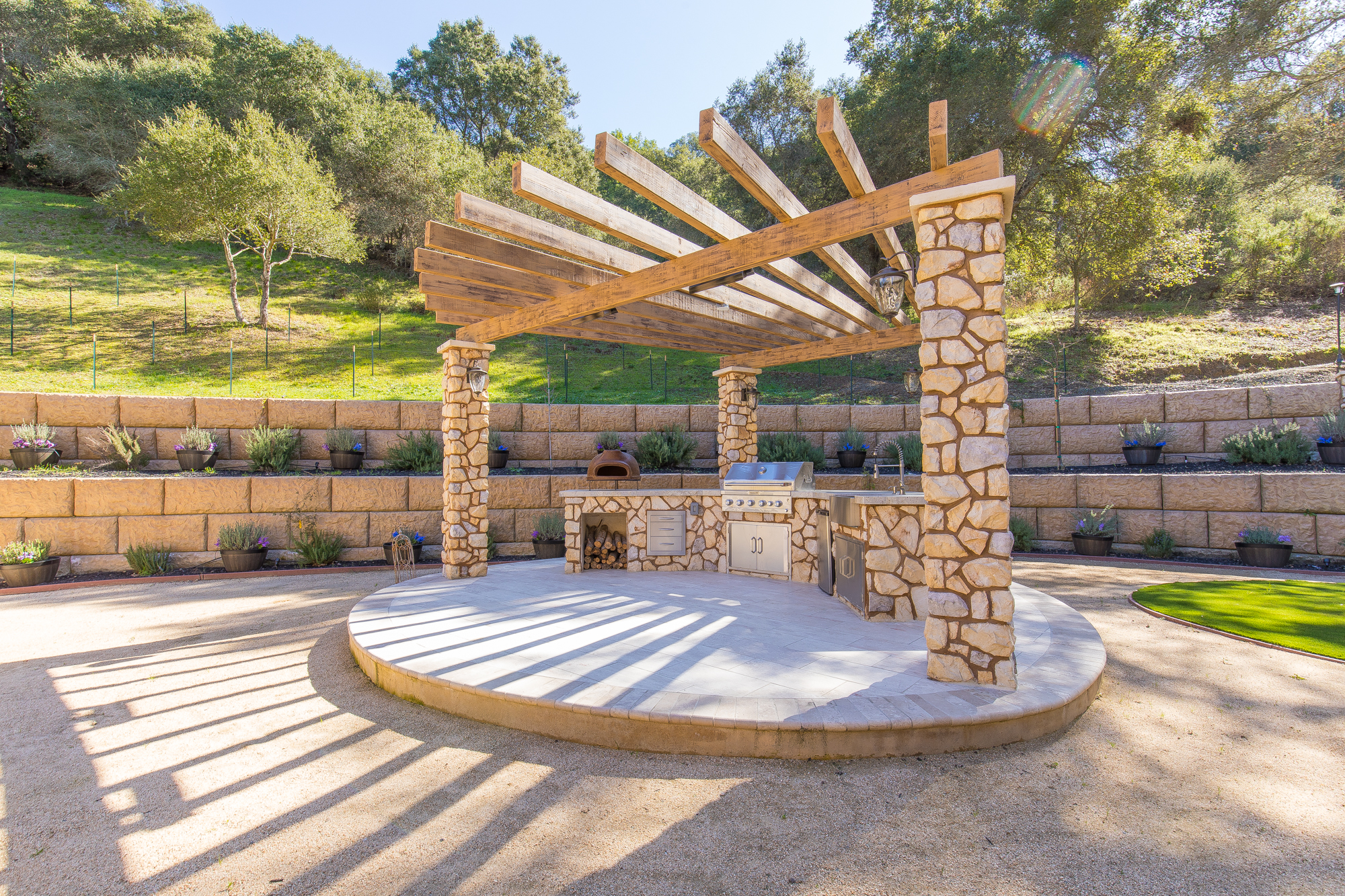  The back yard of the main home features an outdoor kitchen space with a built in BBQ, outdoor sink, clay pizza oven, refrigerator and storage drawers 