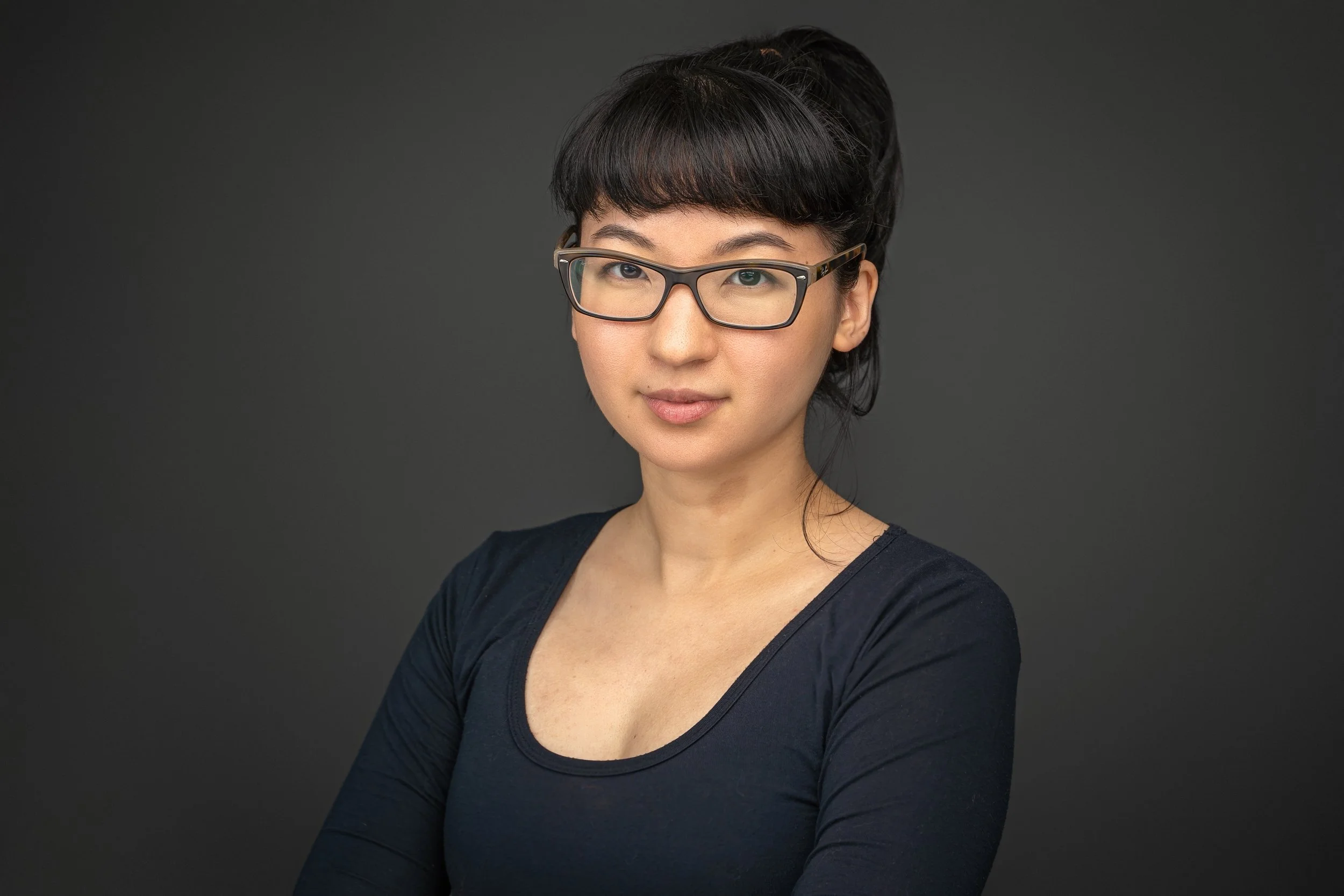 Confident and approachable professional headshot on a dark gray background at Fotoplicity studio in East Brunswick NJ