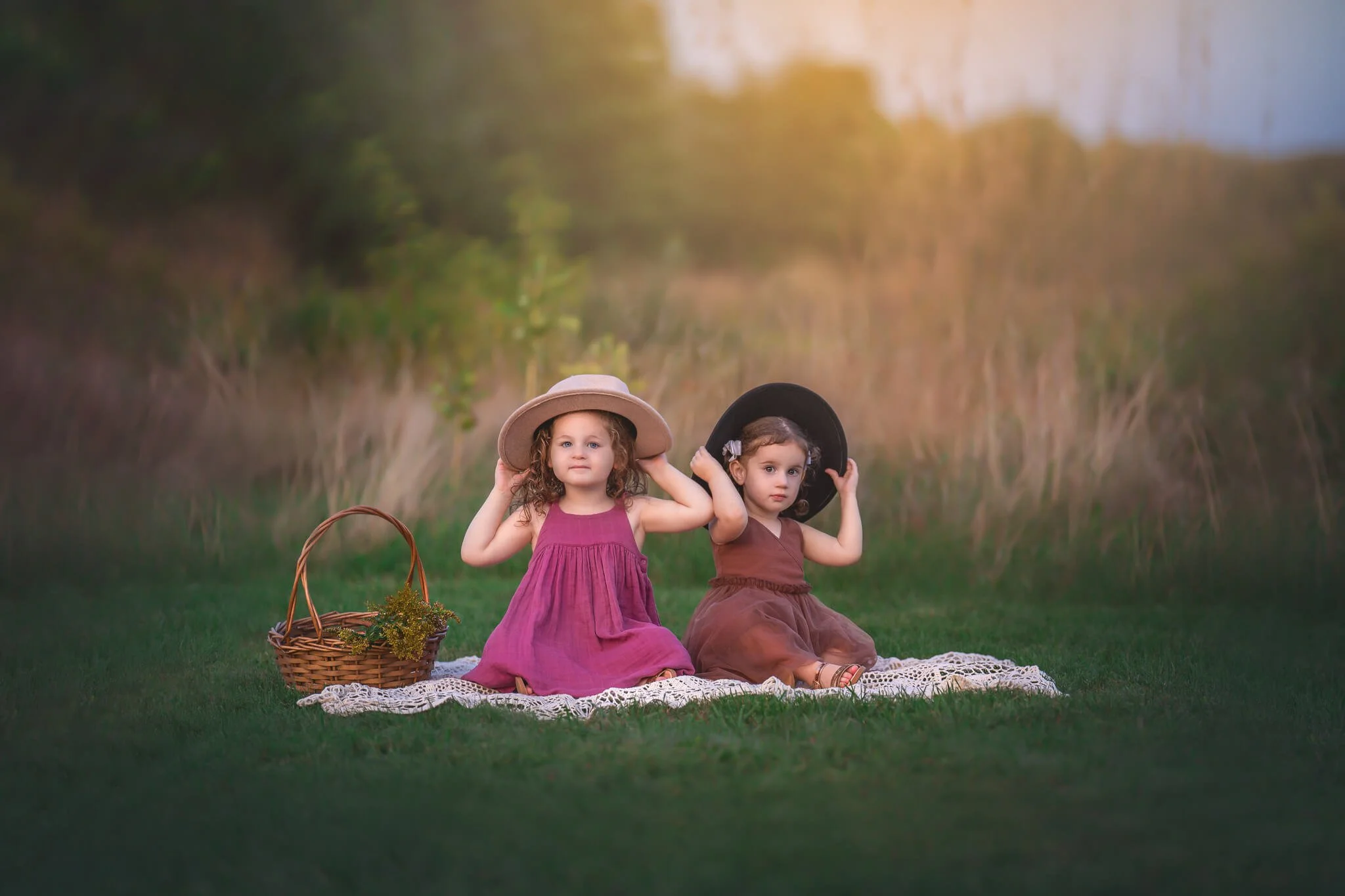 Two young sisters sitting together in a grassy field during an outdoor family photography session in North Brunswick, New Jersey.