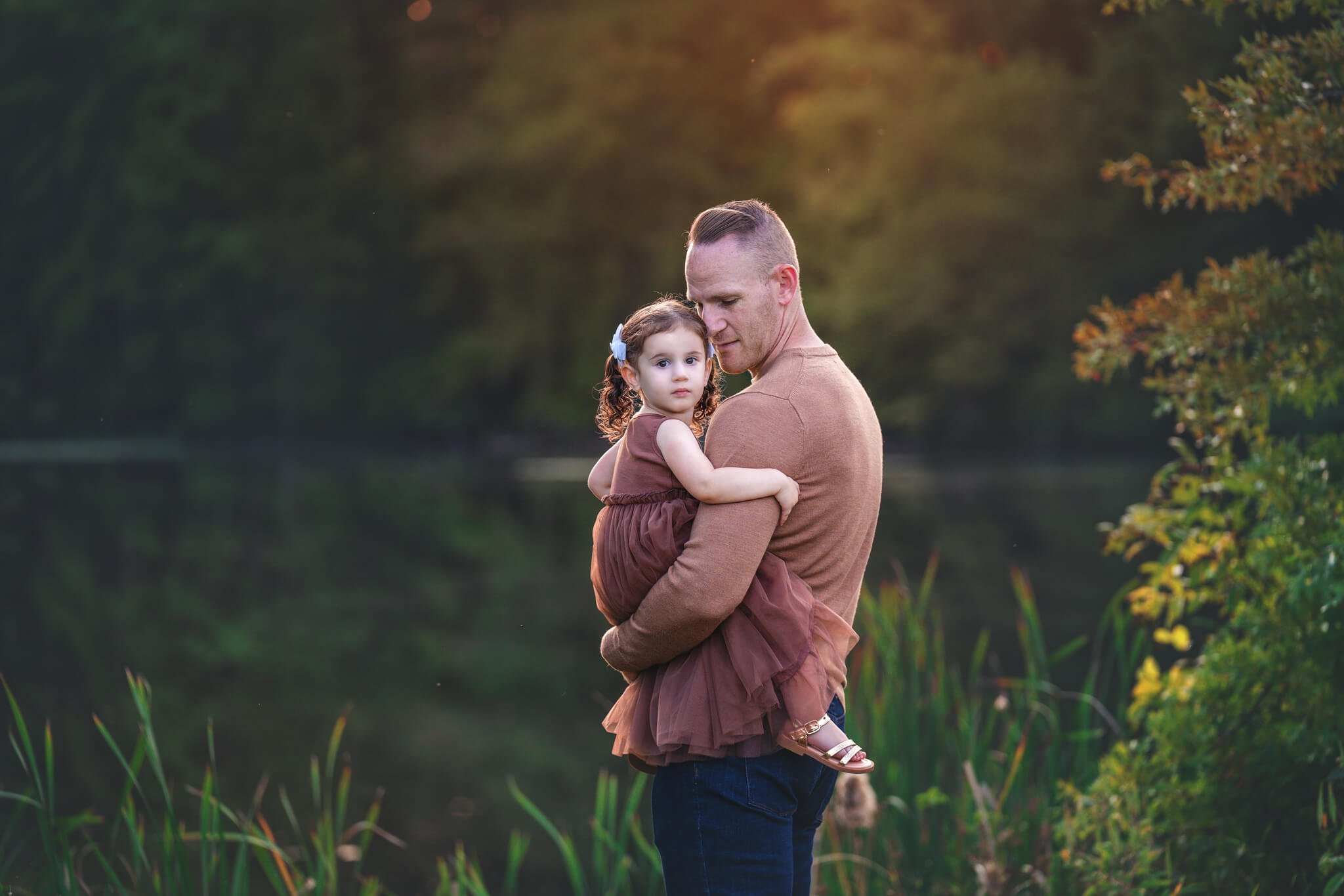Father holding his daughter during a warm golden hour family portrait session in North Brunswick, New Jersey.