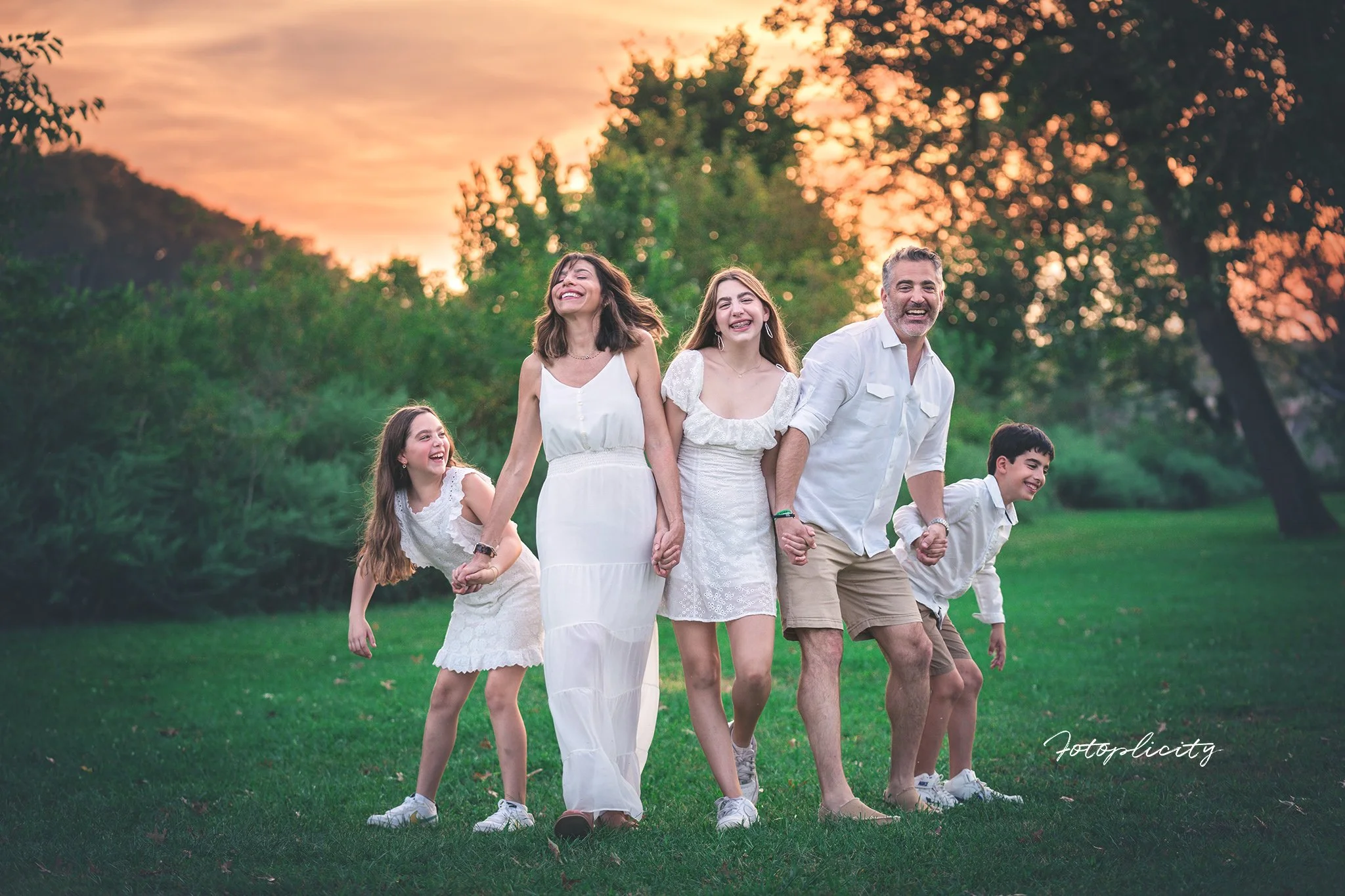 Playful family walking and laughing during a sunset spring outdoor family photography session at Donaldson Park along the Raritan River in Highland Park, New Jersey.