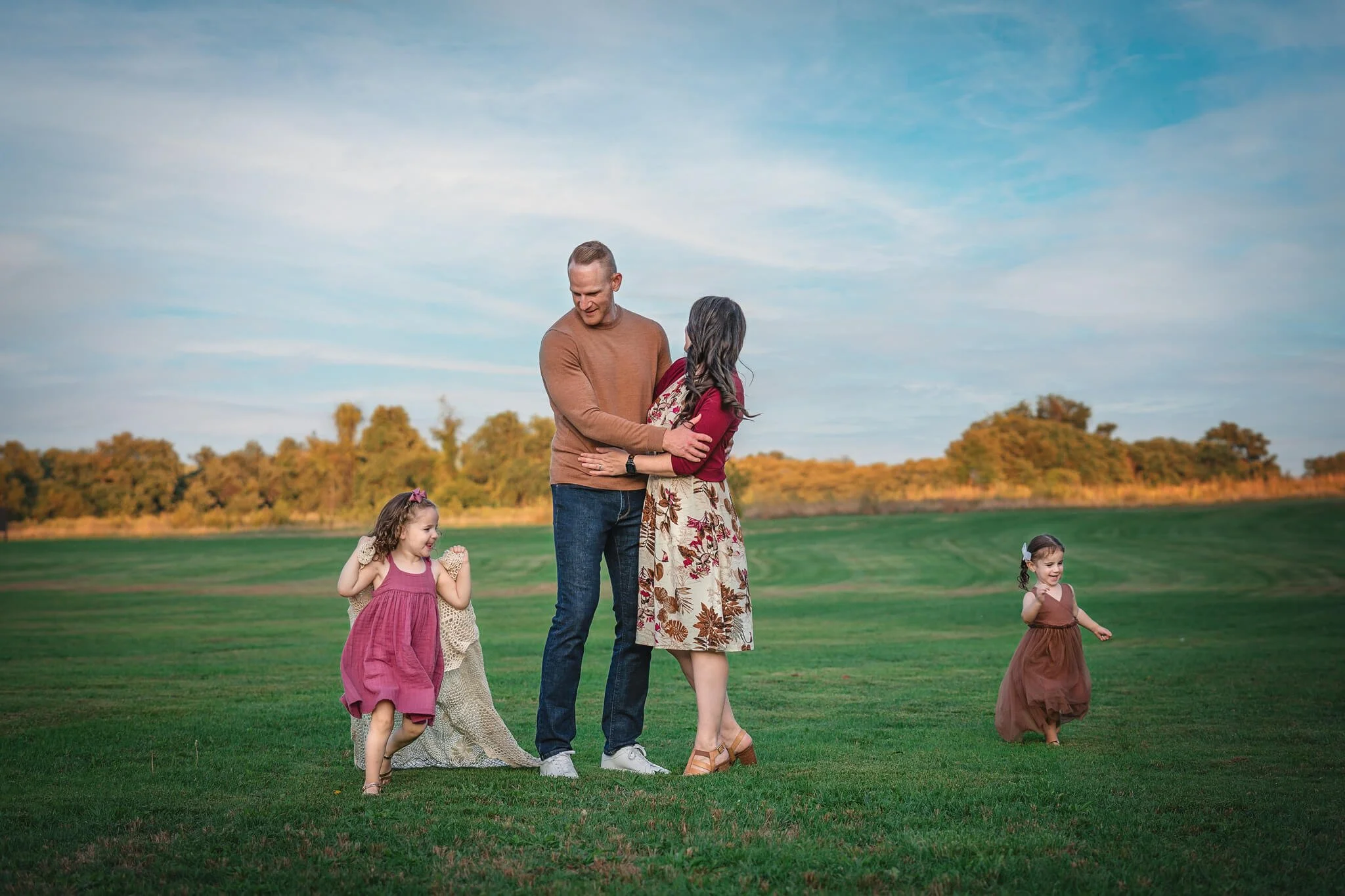 Family walking together across an open field during a natural light family photo session in North Brunswick, New Jersey.