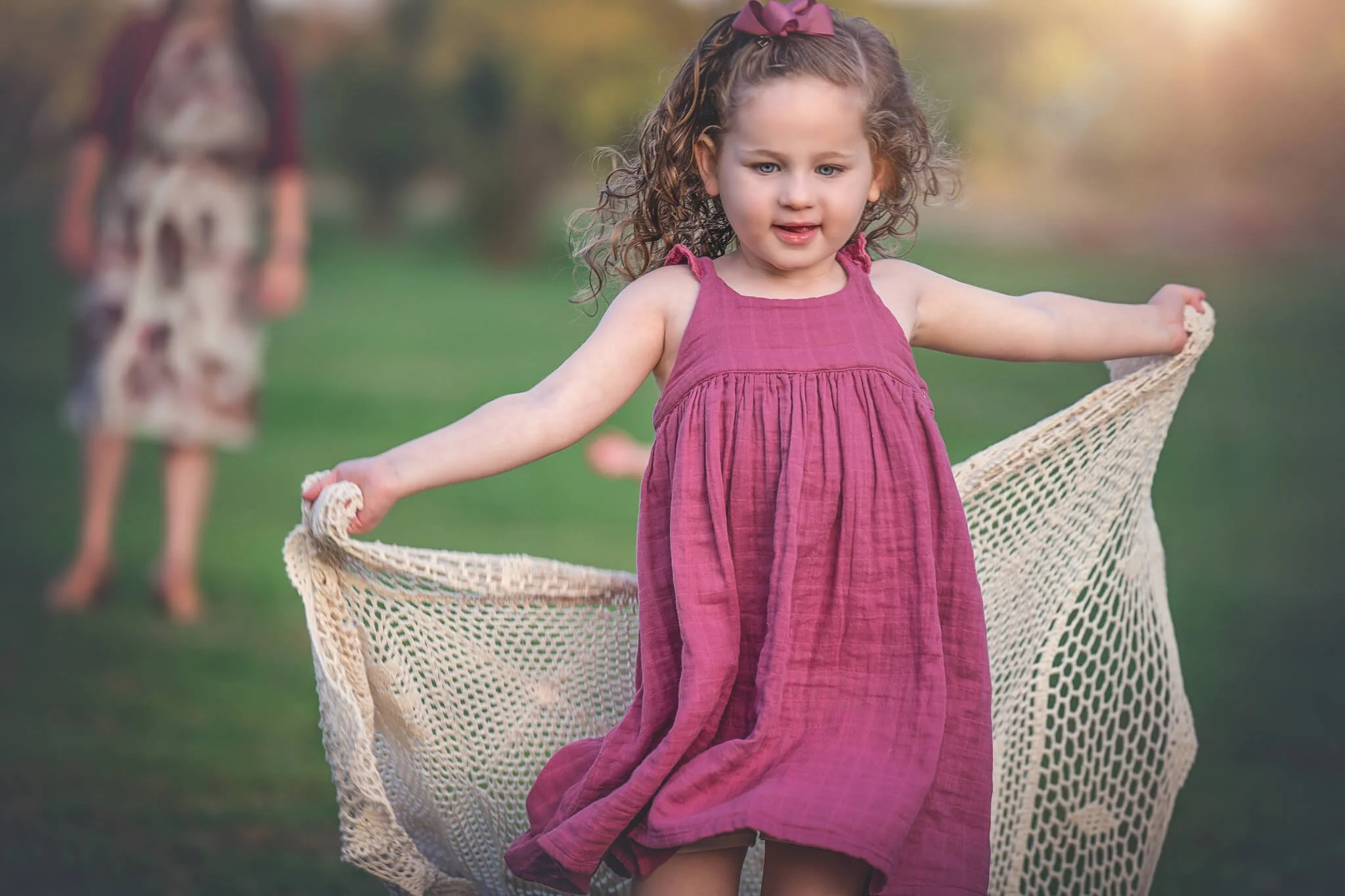 Young girl smiling while playing with a blanket during an outdoor family photography session in North Brunswick, New Jersey.
