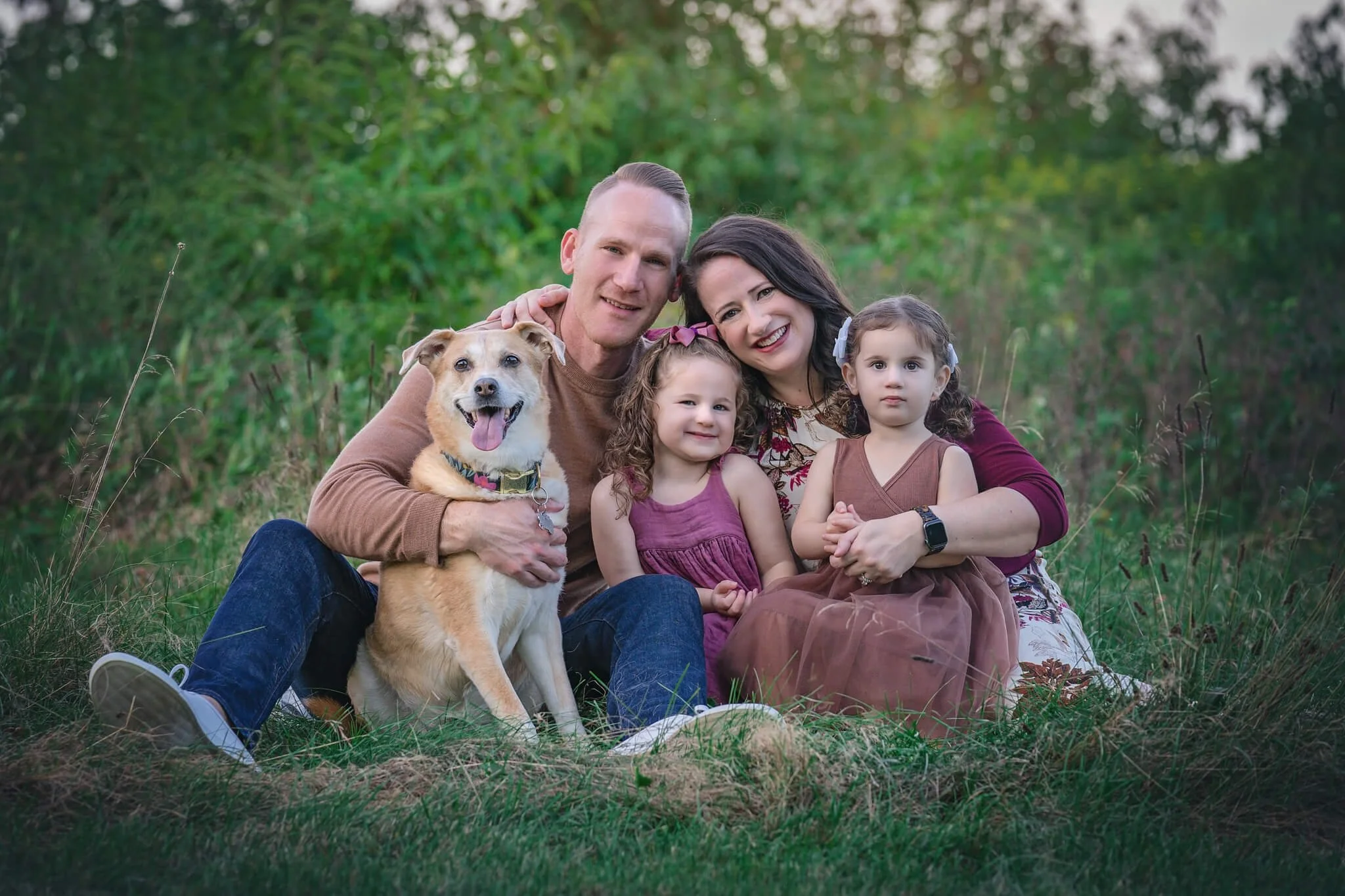 Family of four sitting together with their dog during an outdoor family photo session in North Brunswick, New Jersey.
