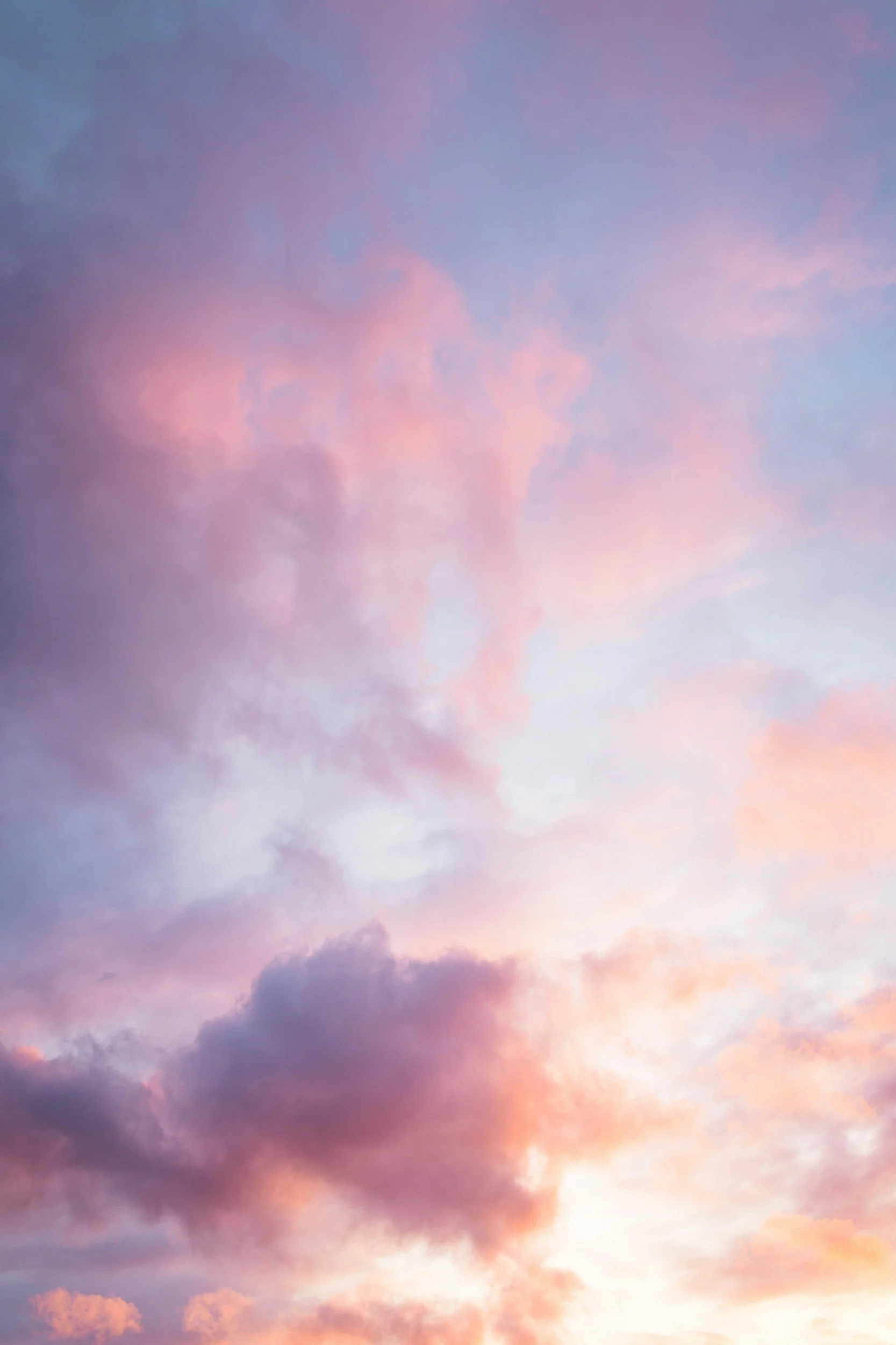 A sky with clouds at sunset, displaying shades of pink, purple, and blue.