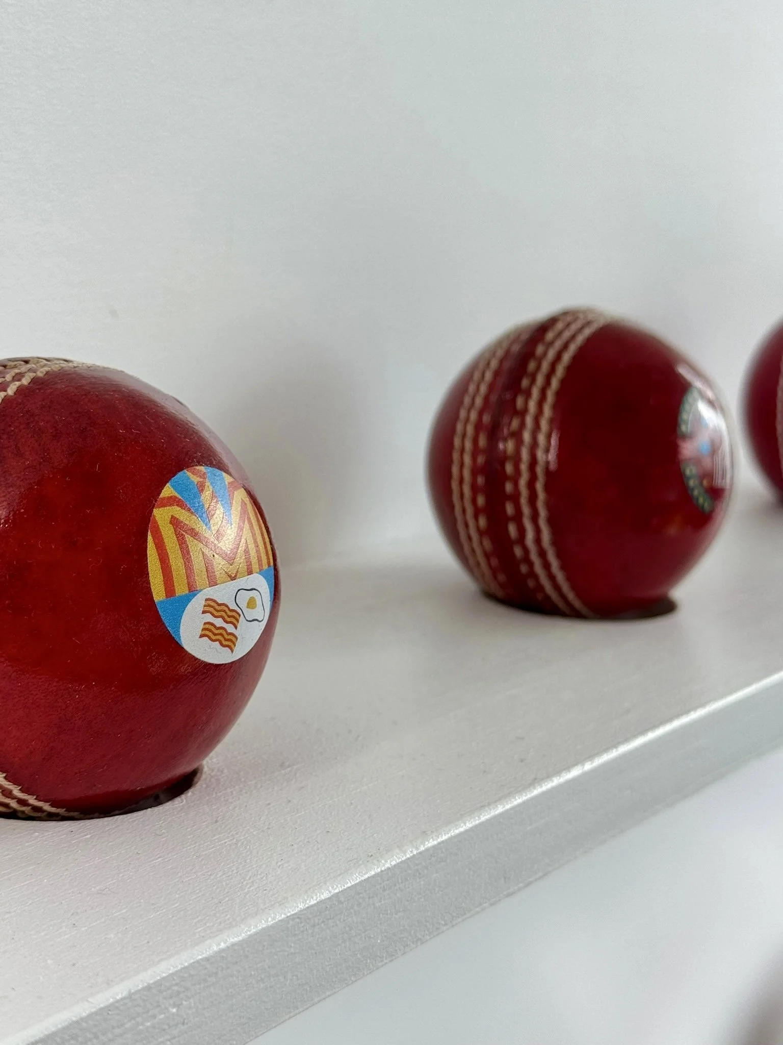 Close-up of two custom-printed red cricket balls