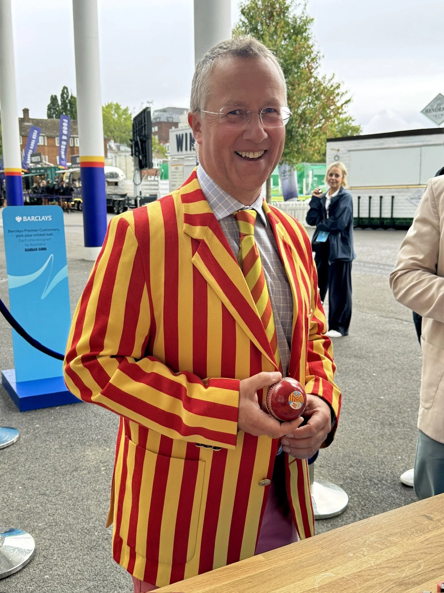 Cricket fan wearing a striped blazer and holding a cricket ball at Lord’s
