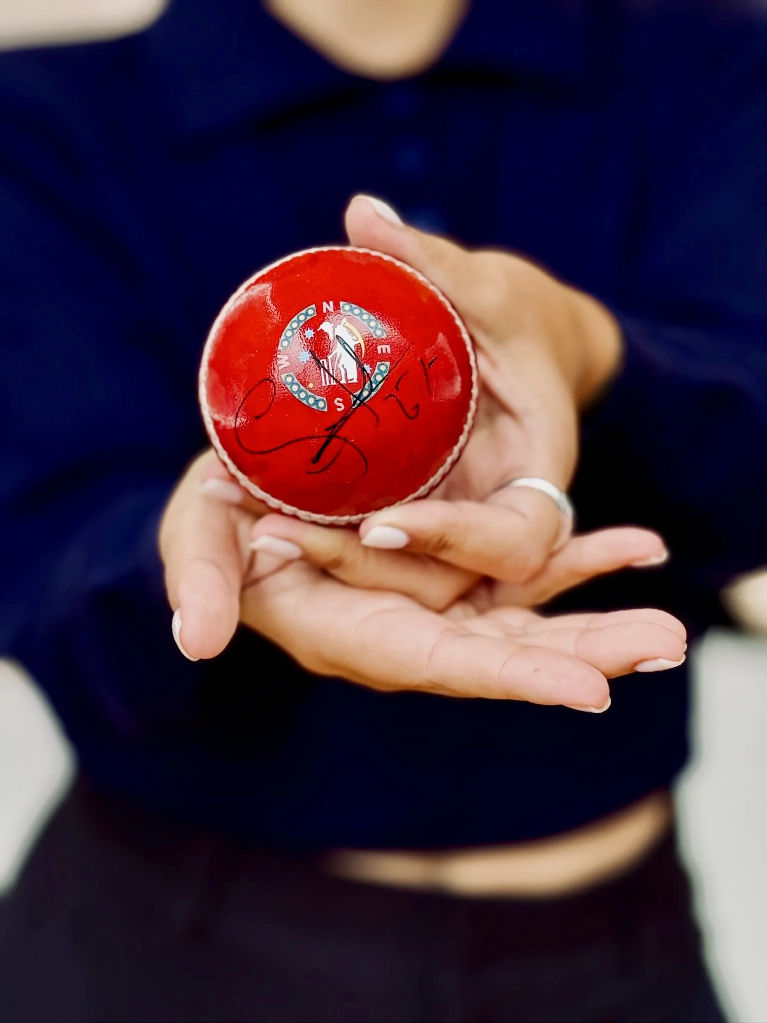 Visitor holding a personalised red cricket ball