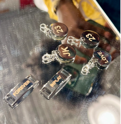 Laser engraved keychains and clips with personalised text displayed on a reflective surface.