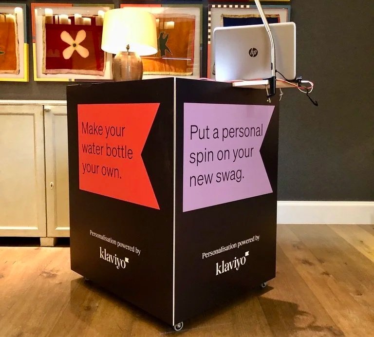 A Klaviyo-branded personalization kiosk at a brand activation event, encouraging guests to customize their water bottle and swag.