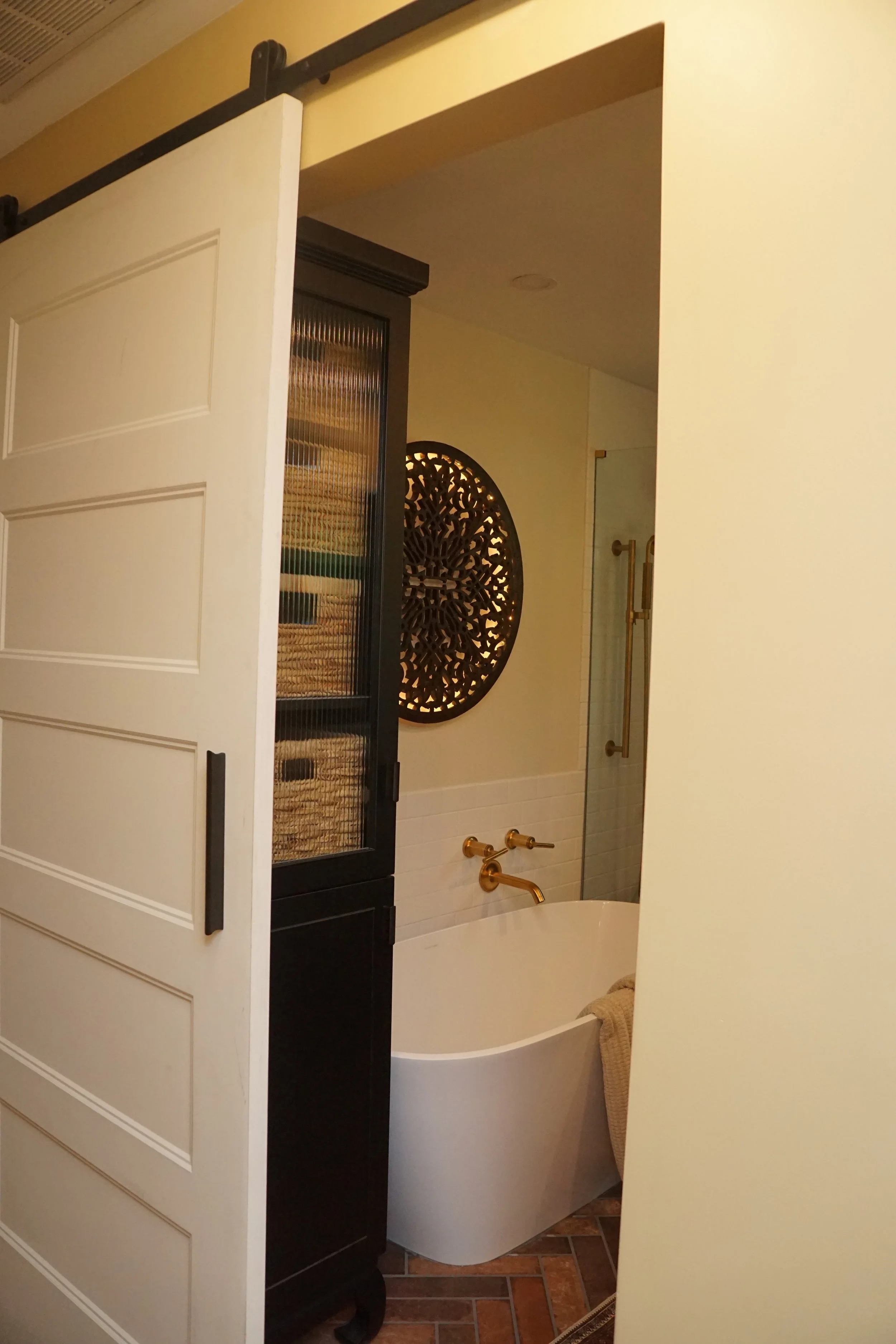  We designed a custom linen closet to mimic the style of the Asian vanity using ebony and matching legs.  The fluted glass helps to keep it from feeling too heavy in this small bathroom. 