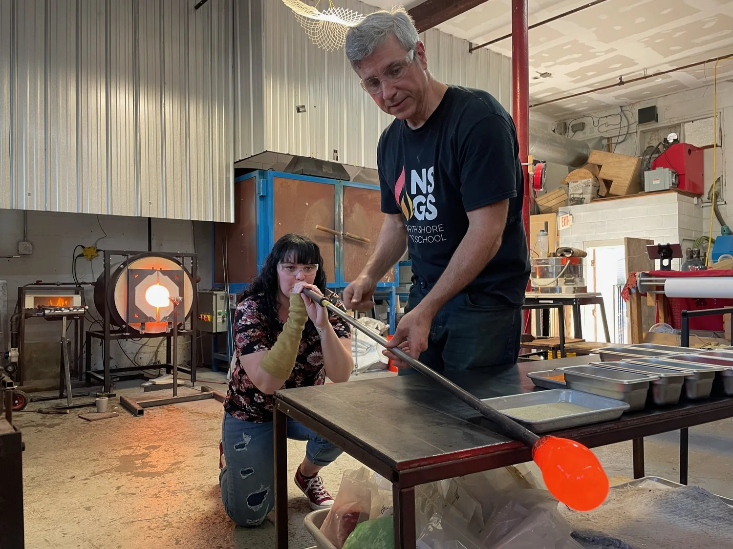 An instructor and student shaping glass at North Shore Glass School
