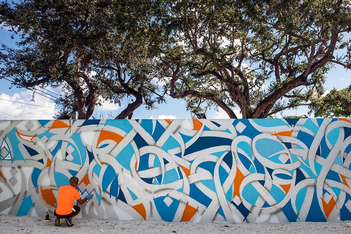 eL Seed AT WORK ON HIS MURAL INSIDE THE WYNWOOD WALLS