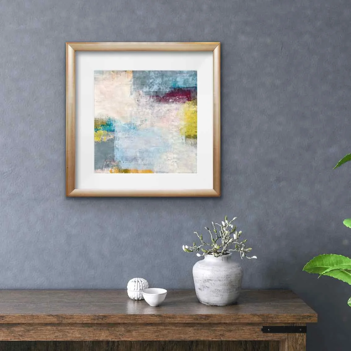 small square framed abstract painting hanging on a wall