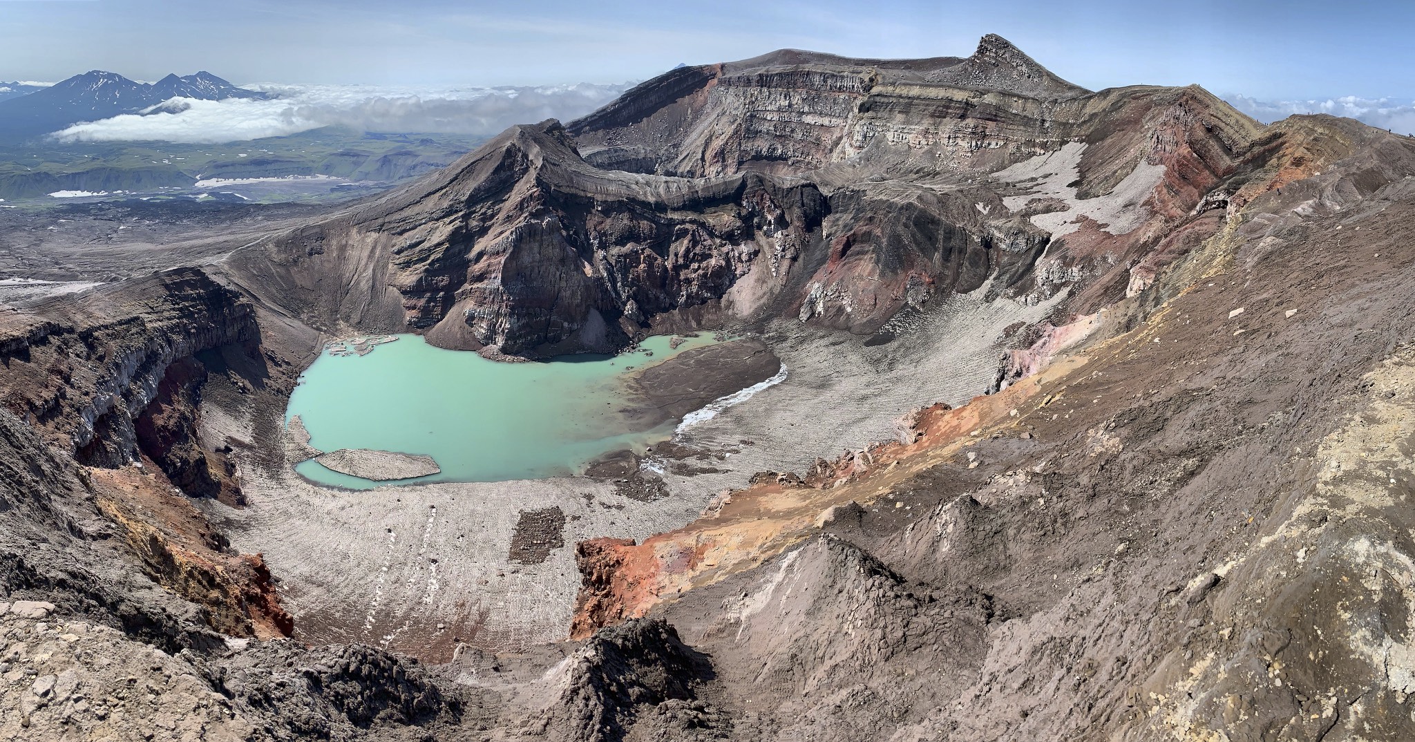 The main crater with a beautiful lake inside. The Gorely Volcano had 9 explosive eruptions in the past. Next to this lake crater is the eruptive crater with an active gas vent. The top of the mountain is the prominent fin in the distance.