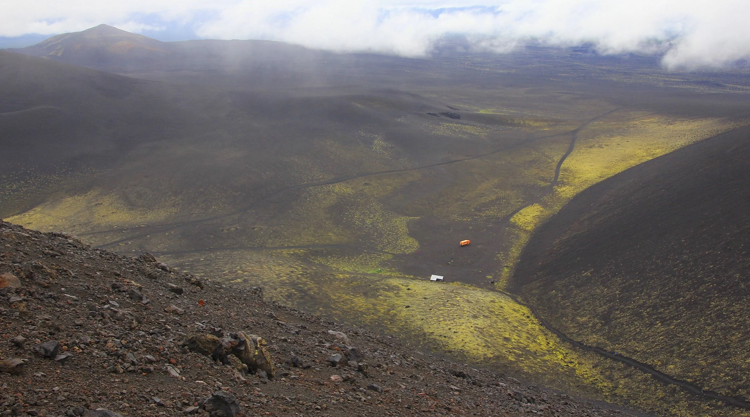 We were waiting for Sergei, our driver, and I hiked up to the top of a volcanic cone next to the shelter. From the top, the desolate landscape spreads out as far as the eye can see. I hiked to the top to warm up as we are getting really cold in the mist and rain.