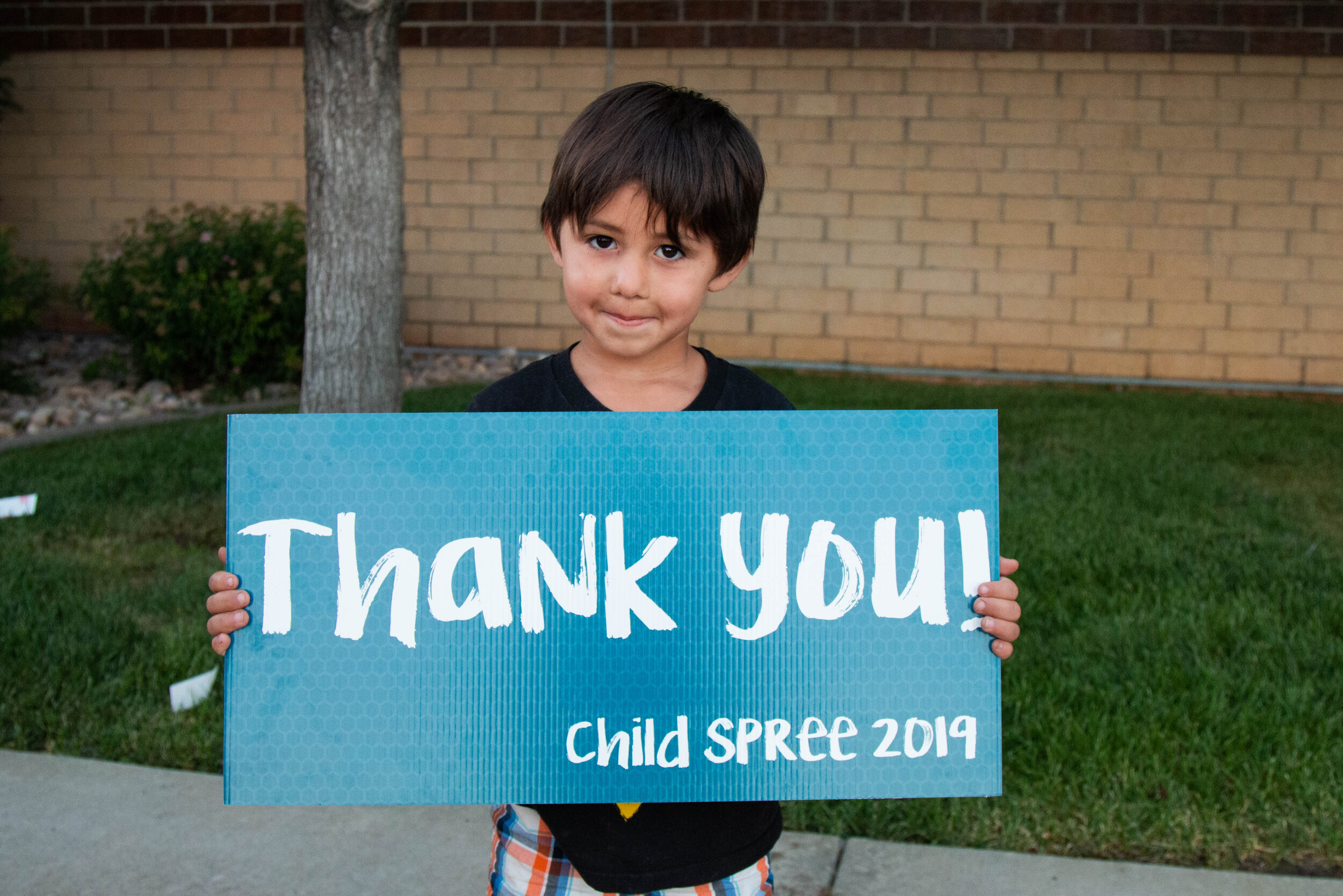 A student poses with a thank-you sign at Child Spree.