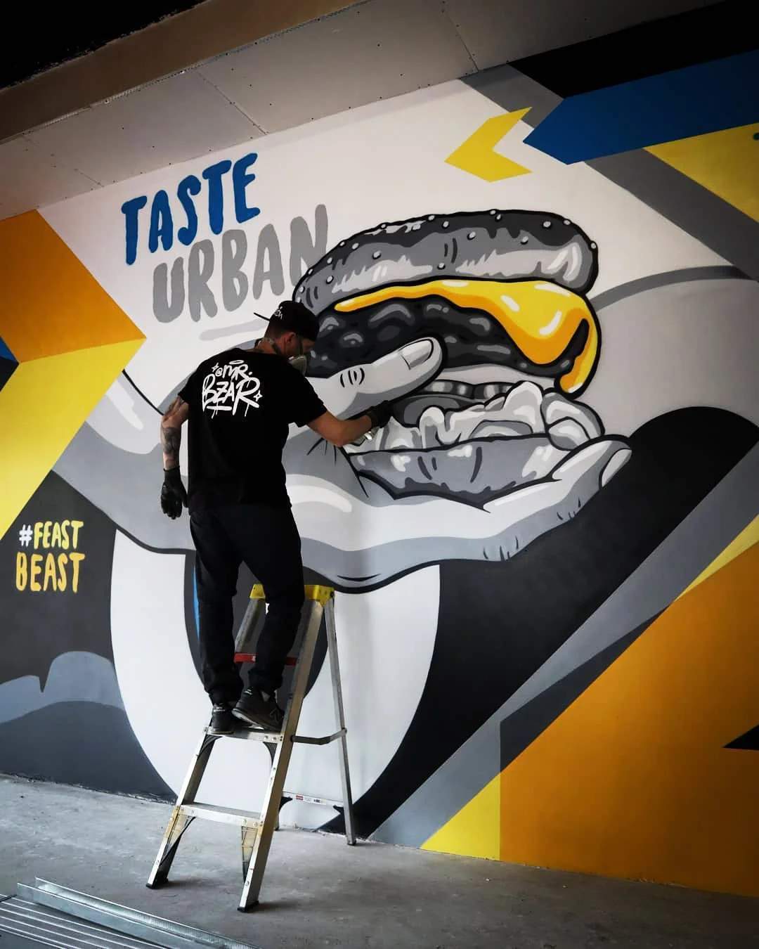 Local graffiti artist Mr Bzar spray painting a commercial mural in a restaurant in Rondebosch, Cape Town
