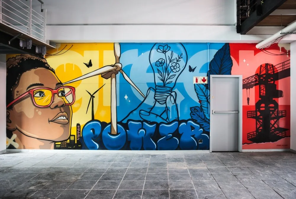 Corporate graffiti mural at USP&E Offices in Salt River featuring green energy imagery, wind turbines, and a stylized portrait in bold brand colours.