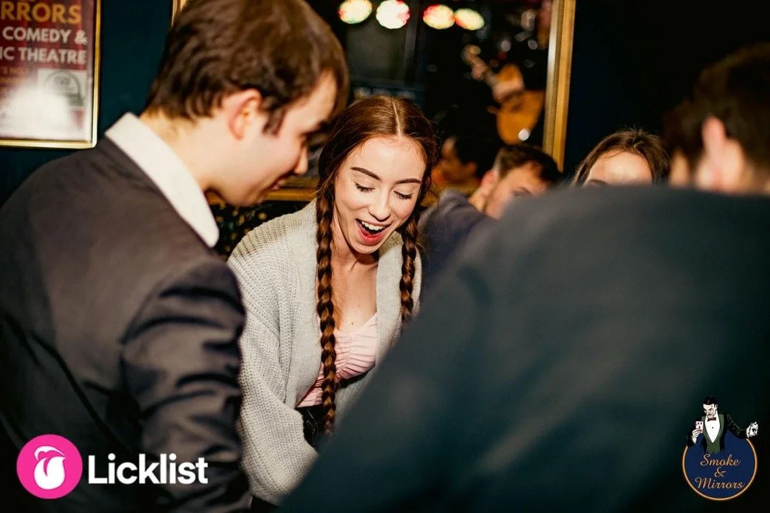 magician performing for a very surprised looking guest in a magic bar.