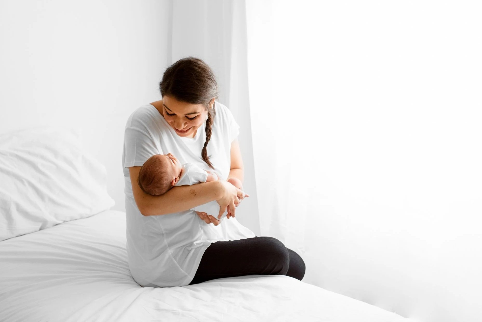 Mum holding her newborn baby during a calm, natural newborn photography session in Wokingham