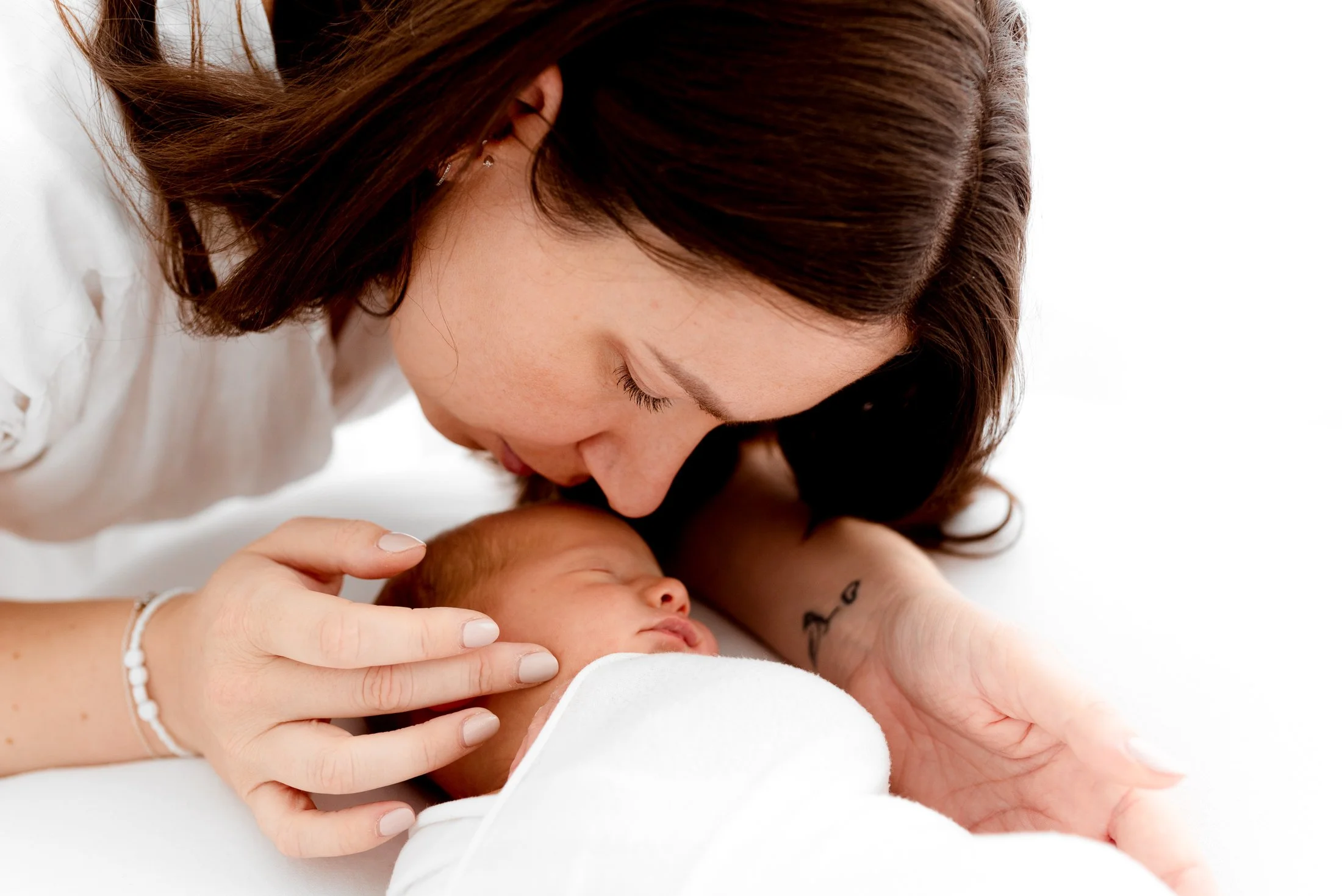 Parent gently comforting their newborn during a calm photoshoot session